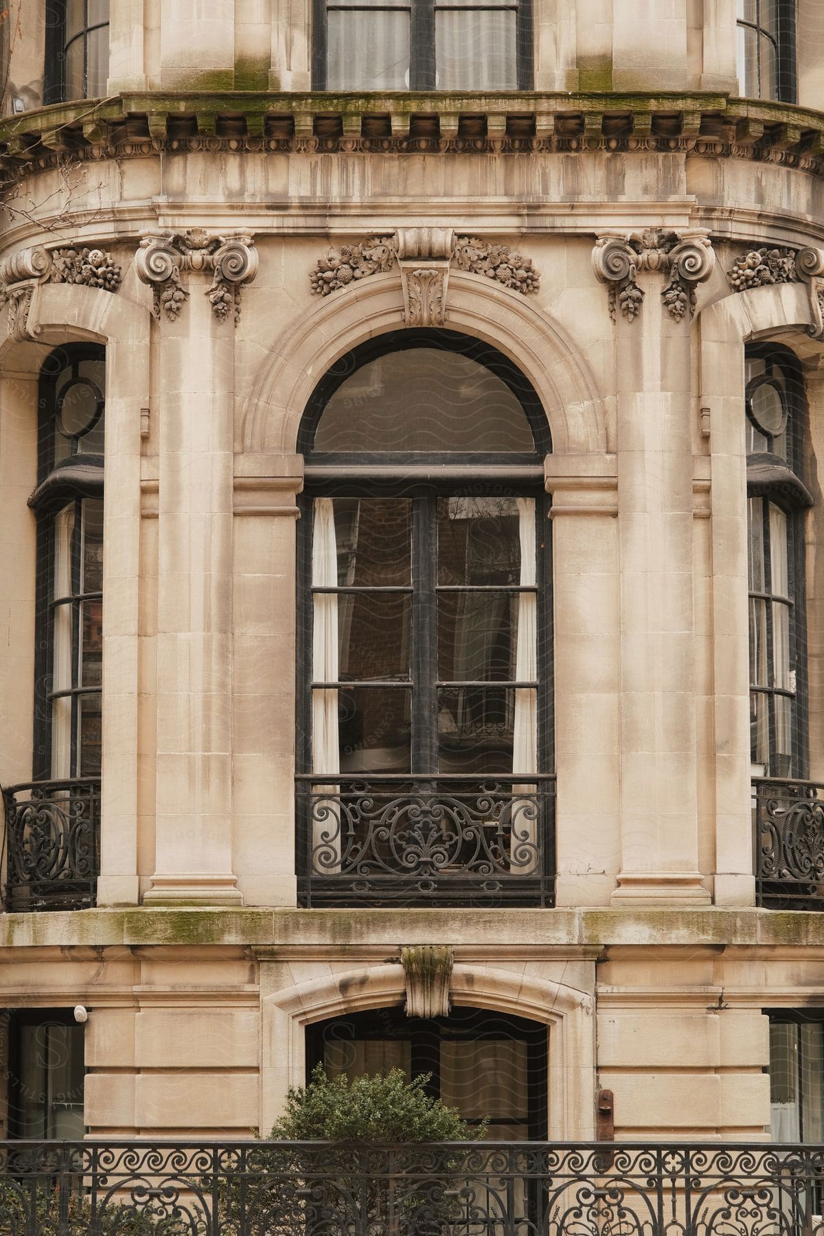 A window in a historic building with wrought iron bars flanked by arches and columns