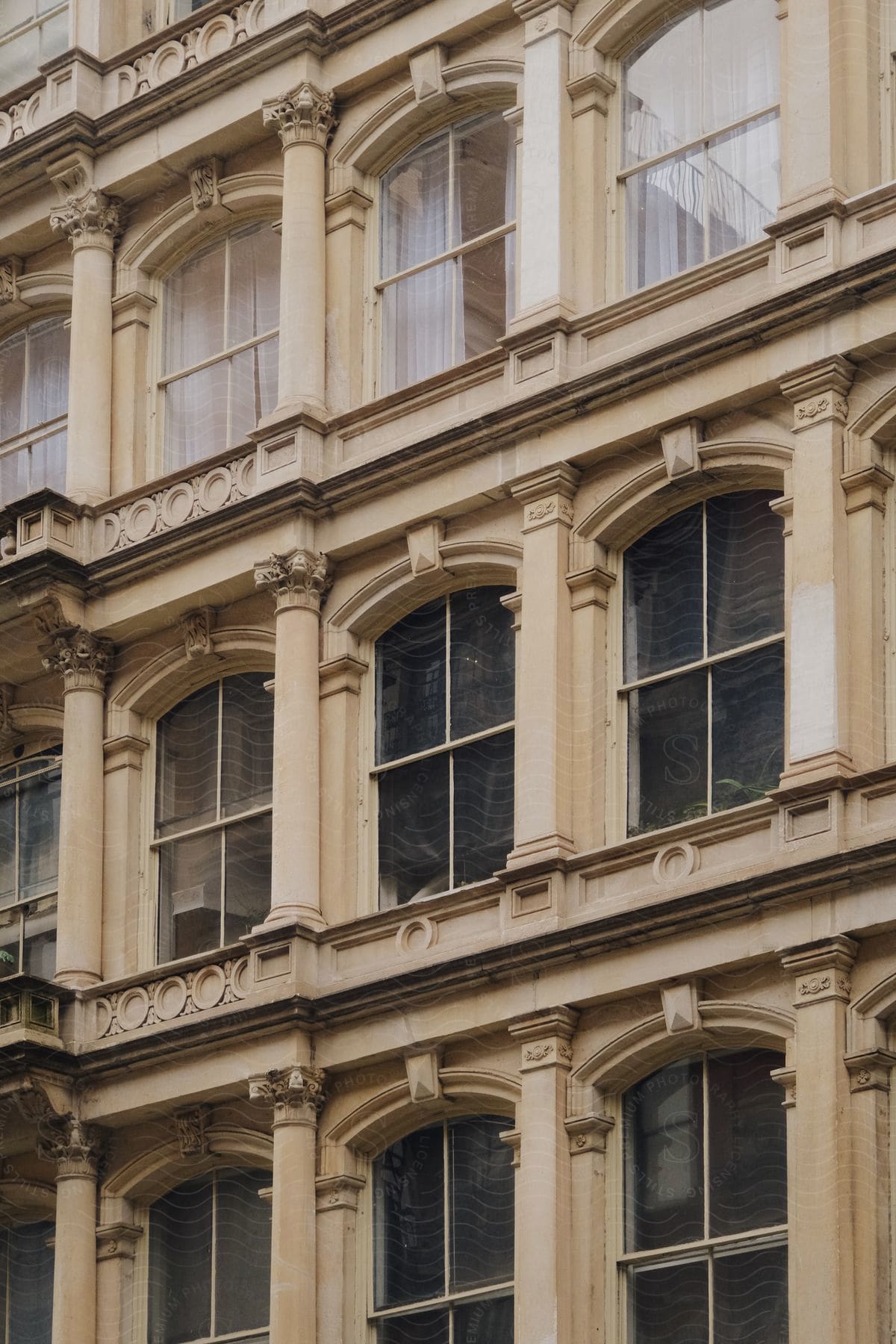 A metropolitan style apartment building with arch windows and a cream color facade