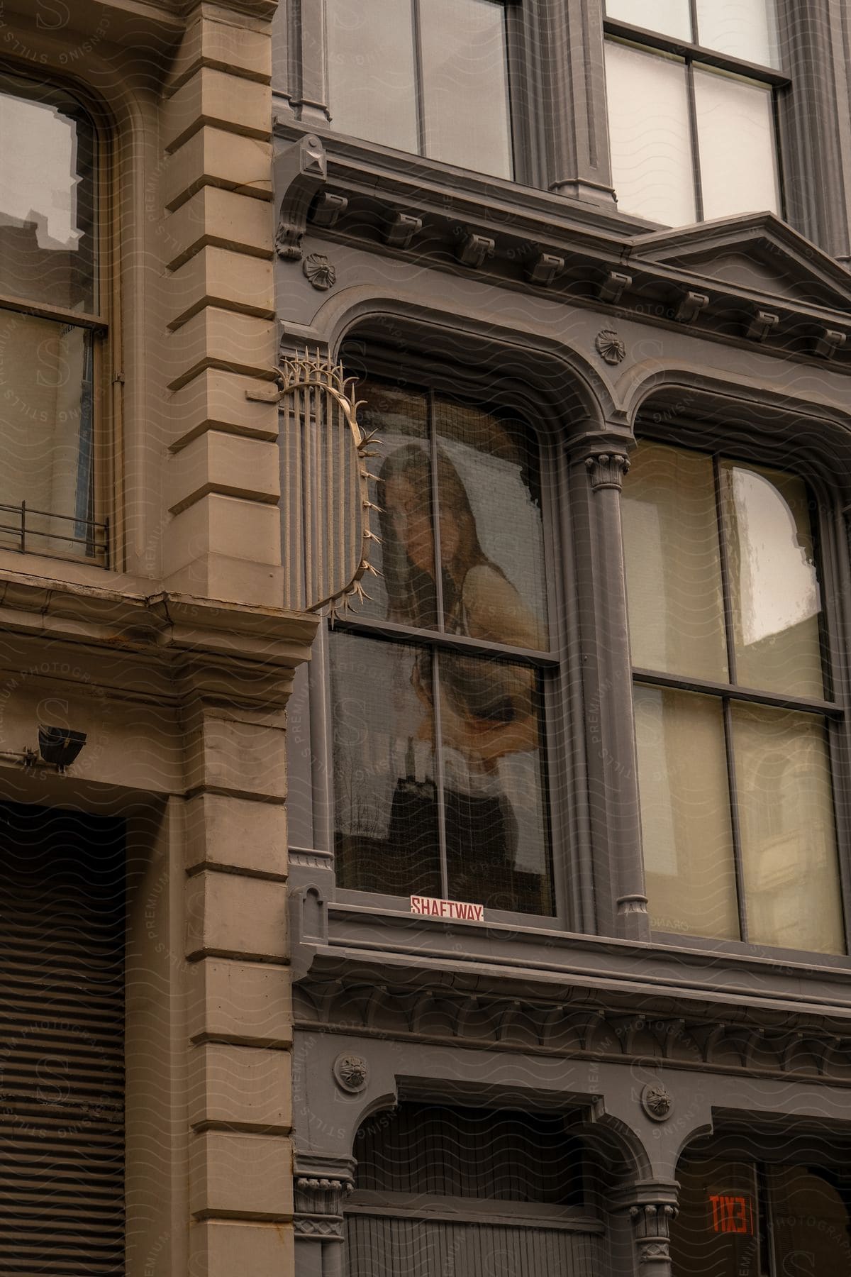 A poster advertisement is displayed in a large window of a historic style building in a city