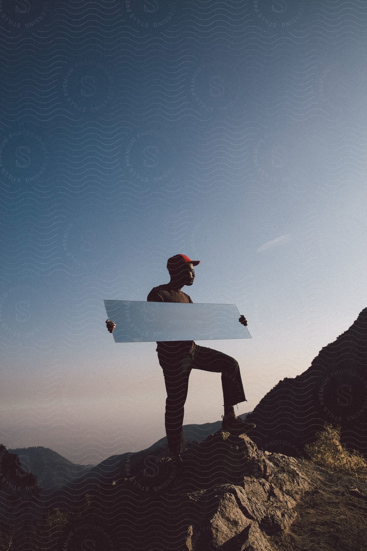 A hiker poses with a mirror on a mountain peak