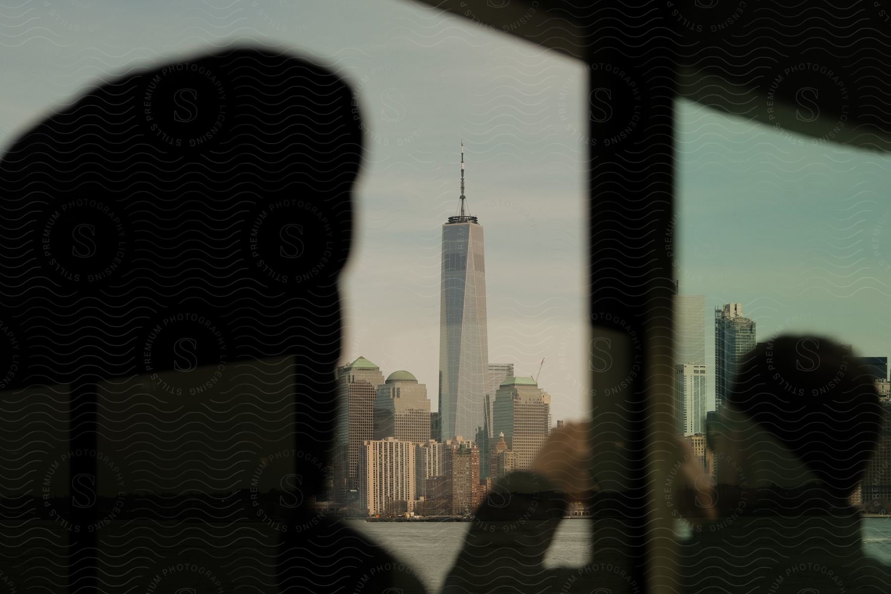 A man takes a photo of a city skyline with tall skyscrapers along the waterfront