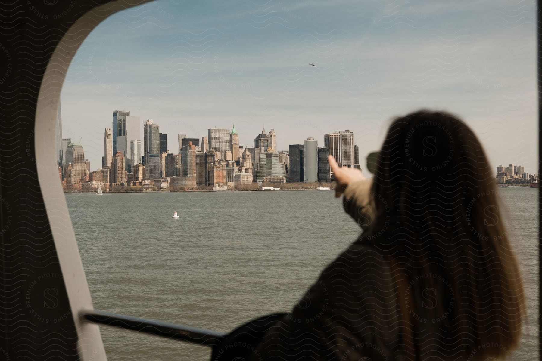 A woman points to a metropolis across a body of water from a ferry