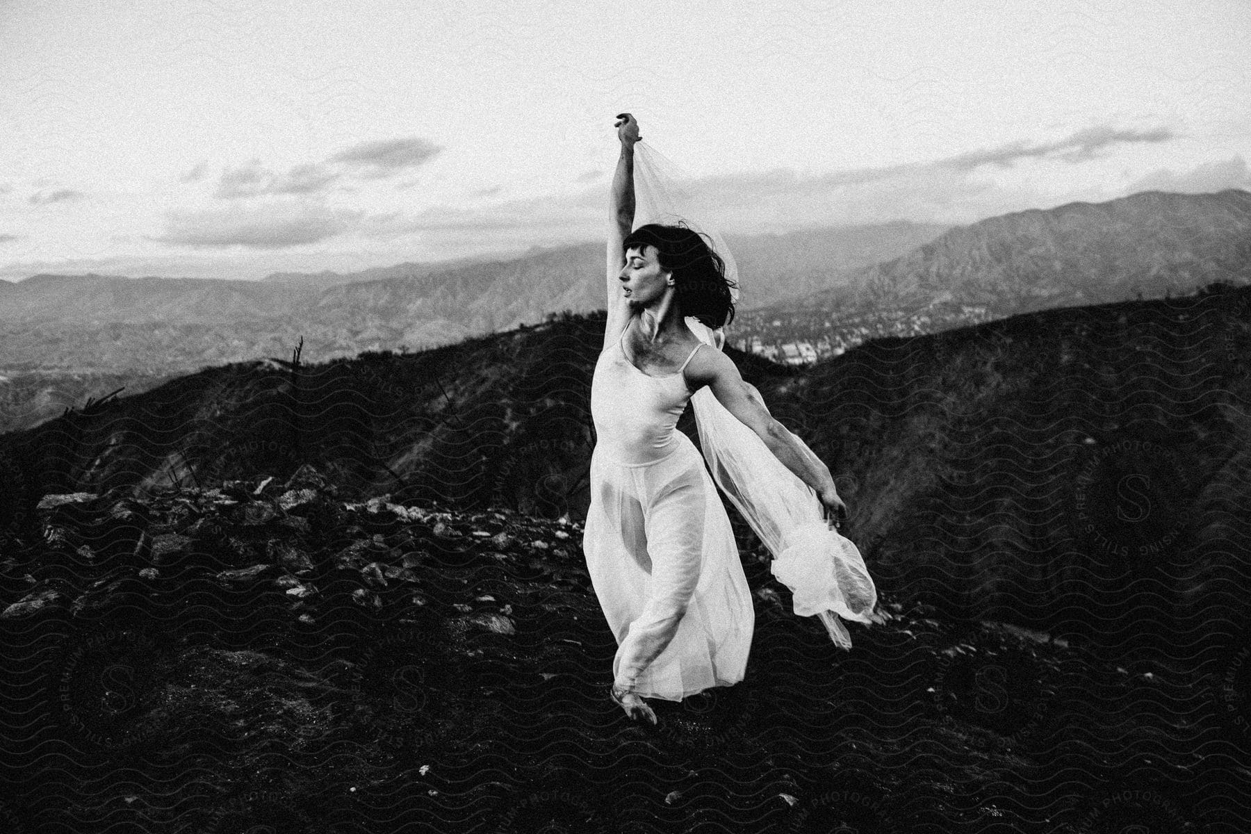 A black and white photo of a woman in a flowing gown gracefully holding a scarf