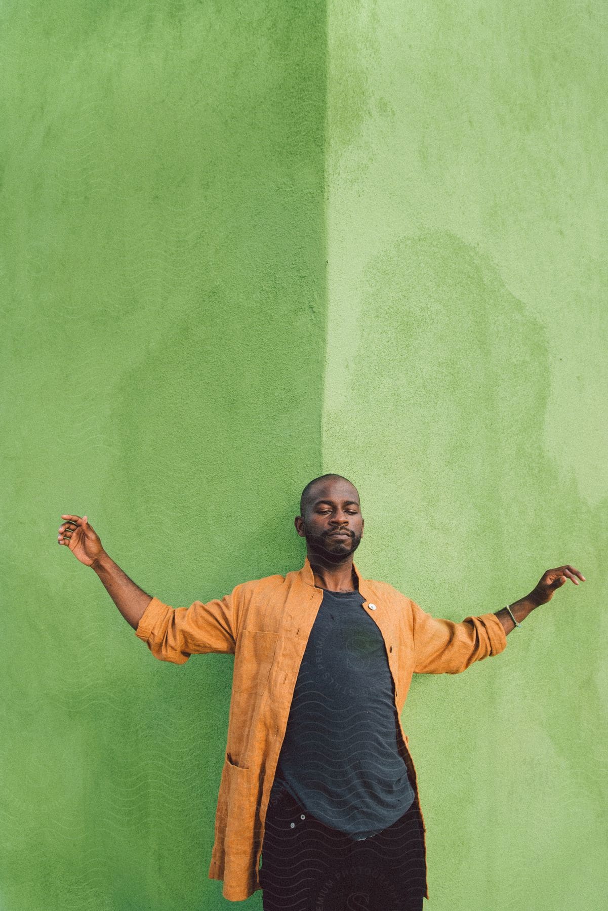 A man stands in front of a green wall