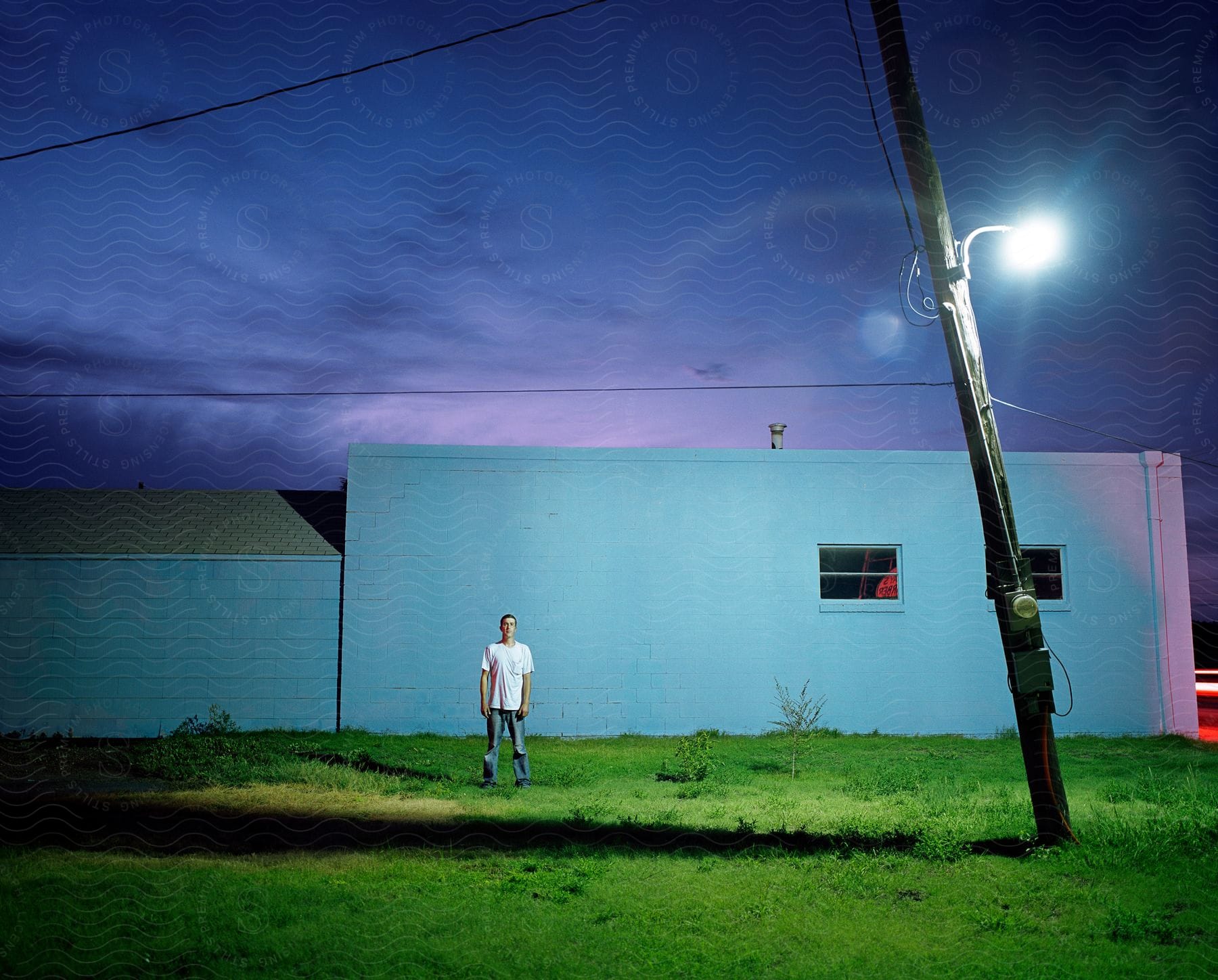 A man stands by a building at night time