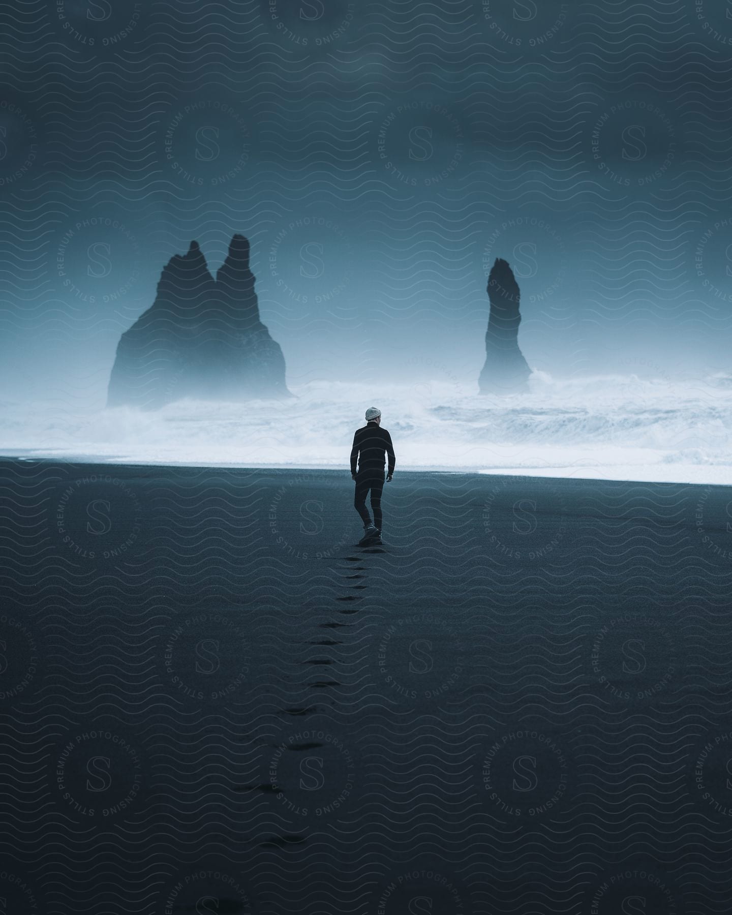 Man dressed in black walking on the reynisfjara beach at night