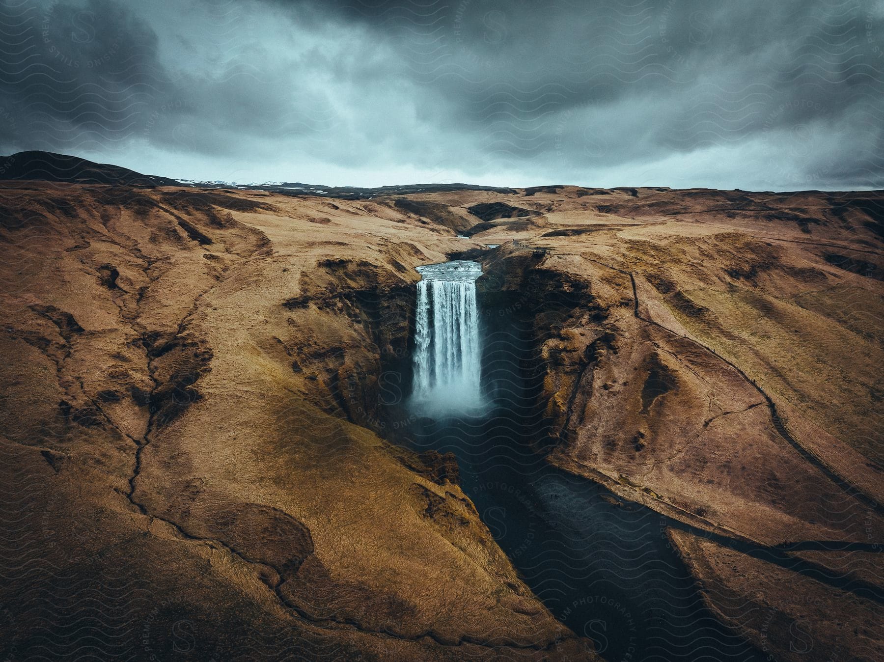 A waterfall flowing over a mountain cliff on a cloudy day