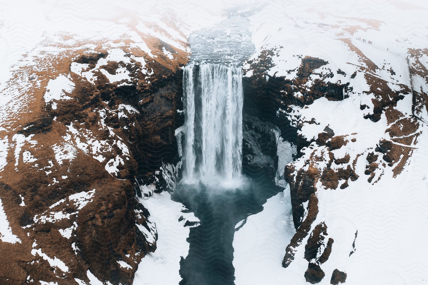 A river running into a large waterfall over a snowy canyon