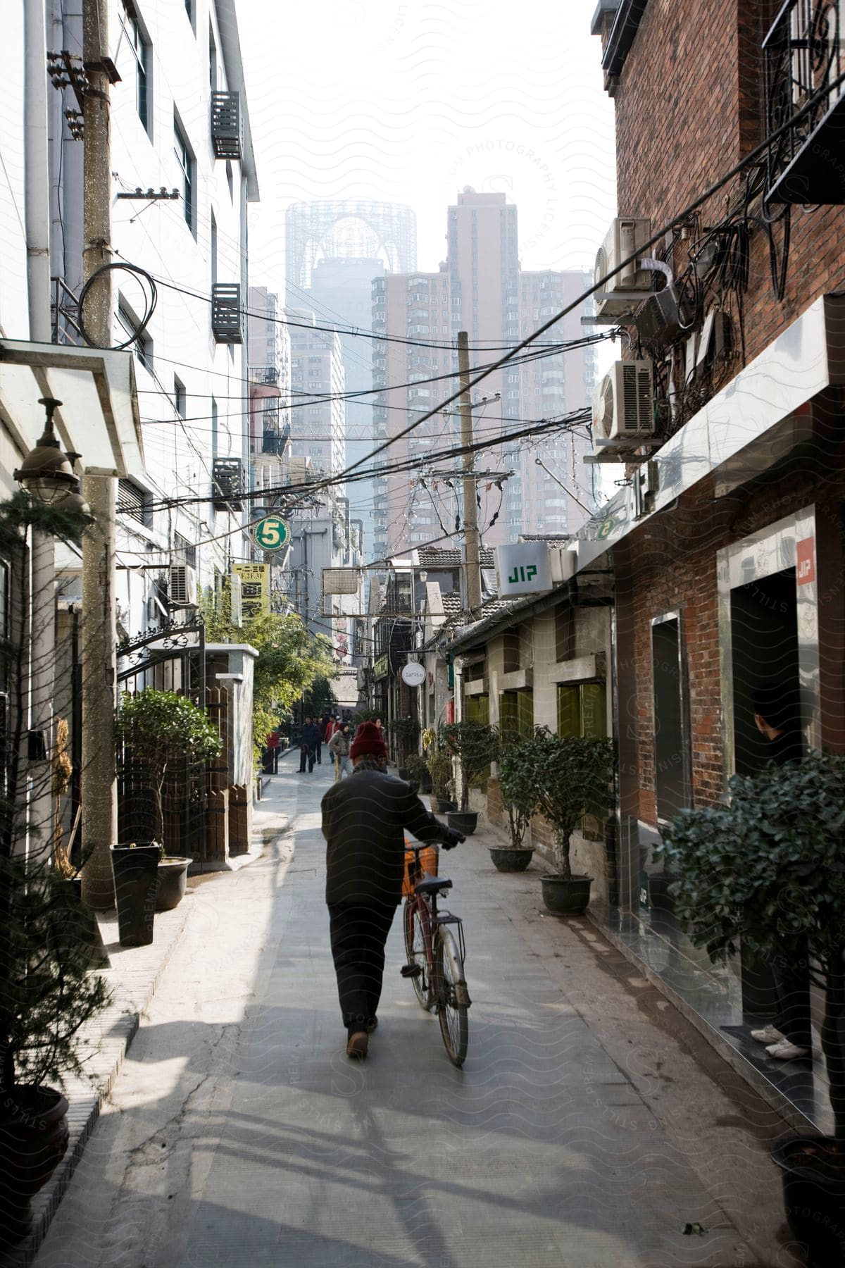 Man pushing bicycle along narrow city alley between apartment buildings
