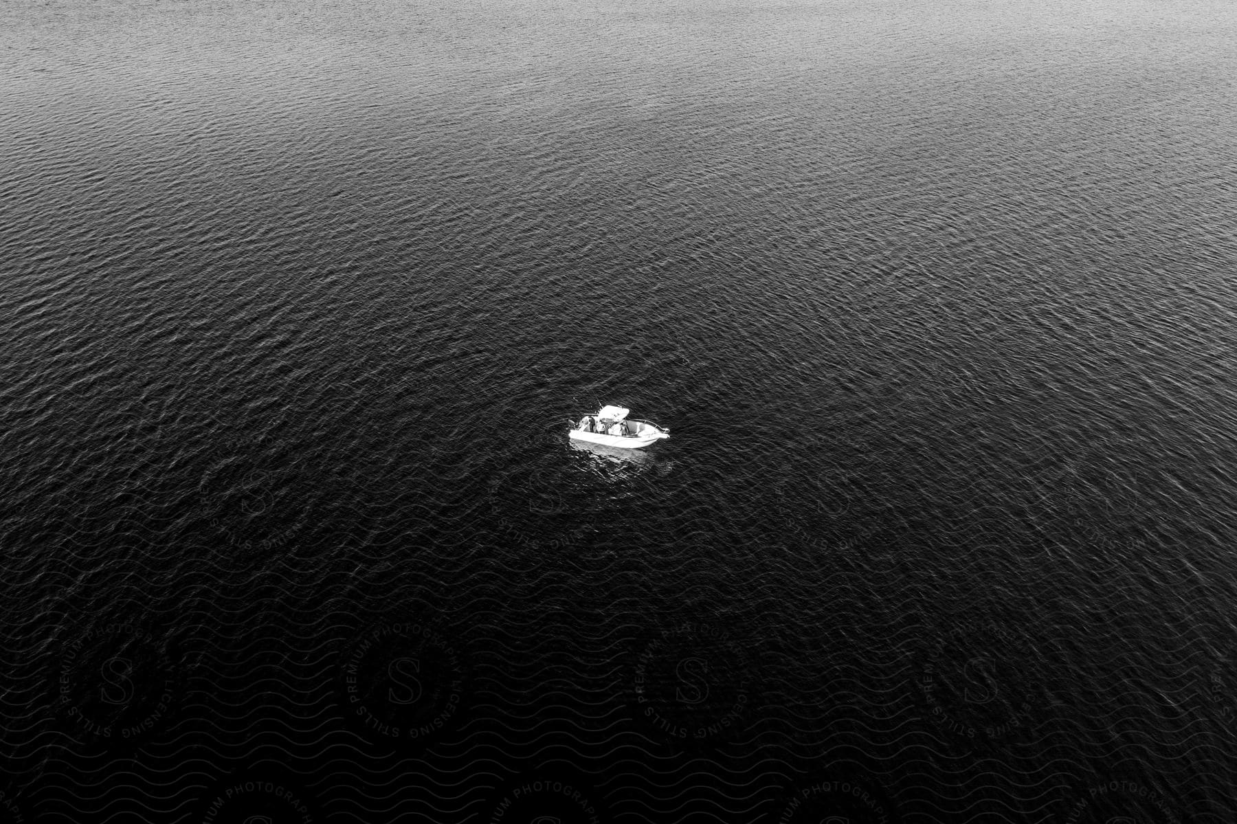 A small boat sails on open water with sunlight reflecting on the ripples