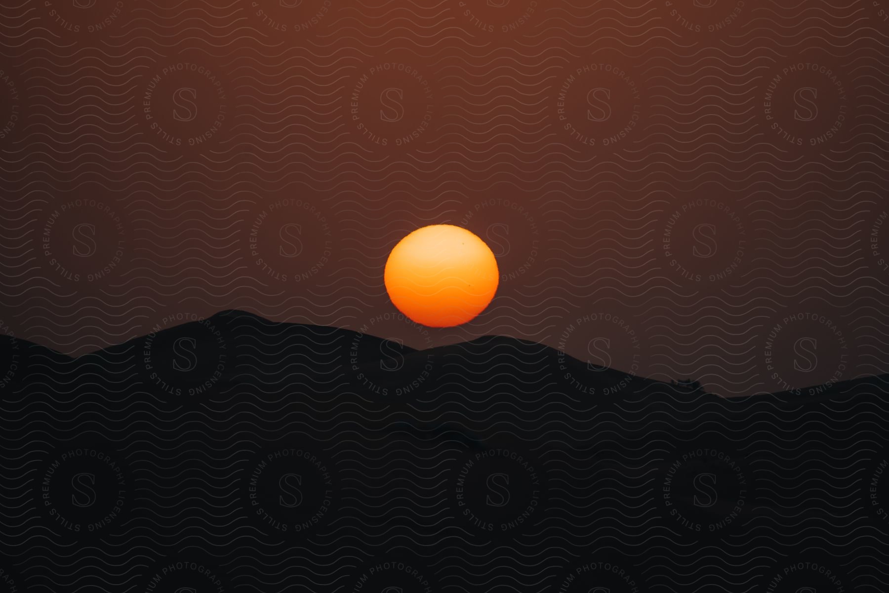 A landscape with the sun setting on the horizon