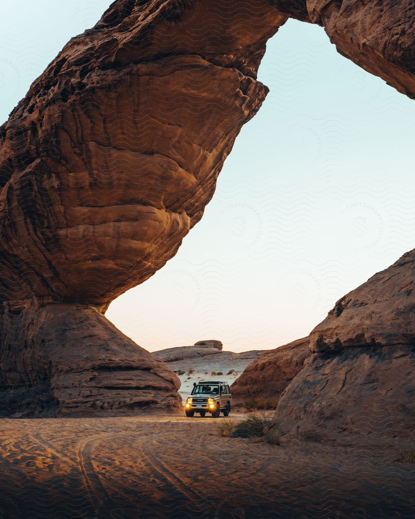 A truck drives through a rock arch in the desert badlands