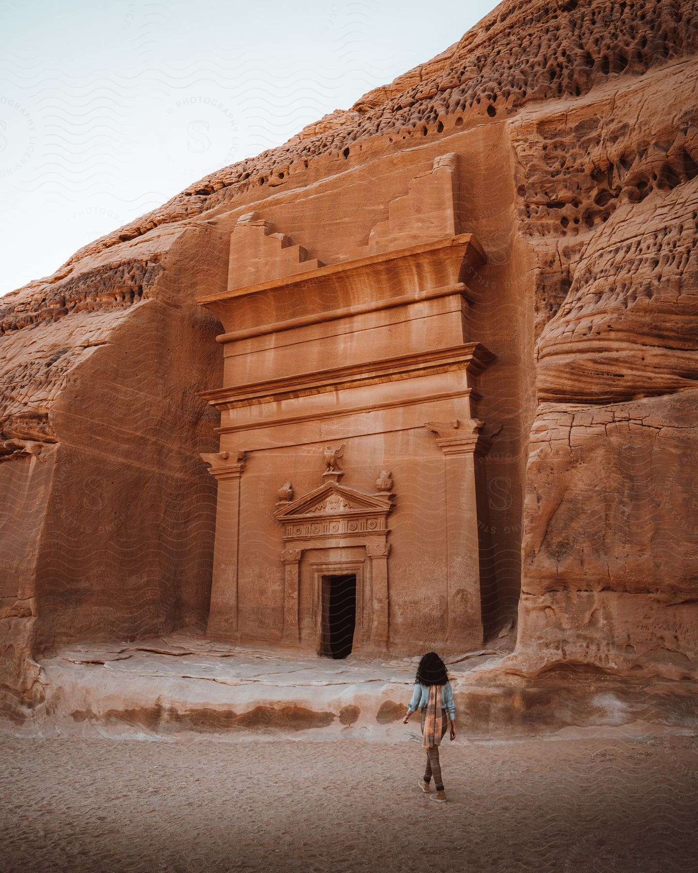 A Woman Walks In The Ancient Historical City Madain Saleh In Saudi Arabia Near An Ancient Building