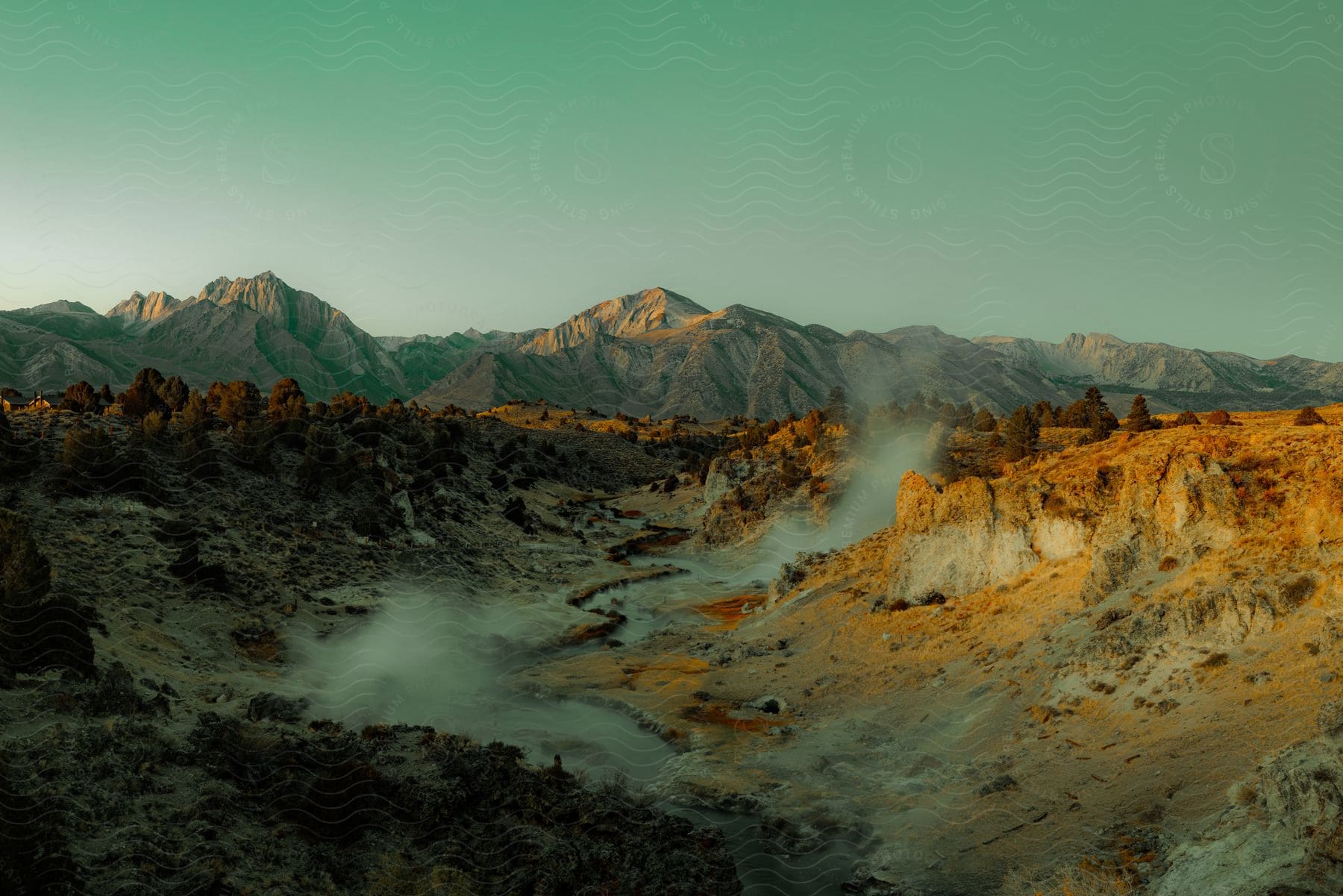 A landscape photograph of hot creek and mountains