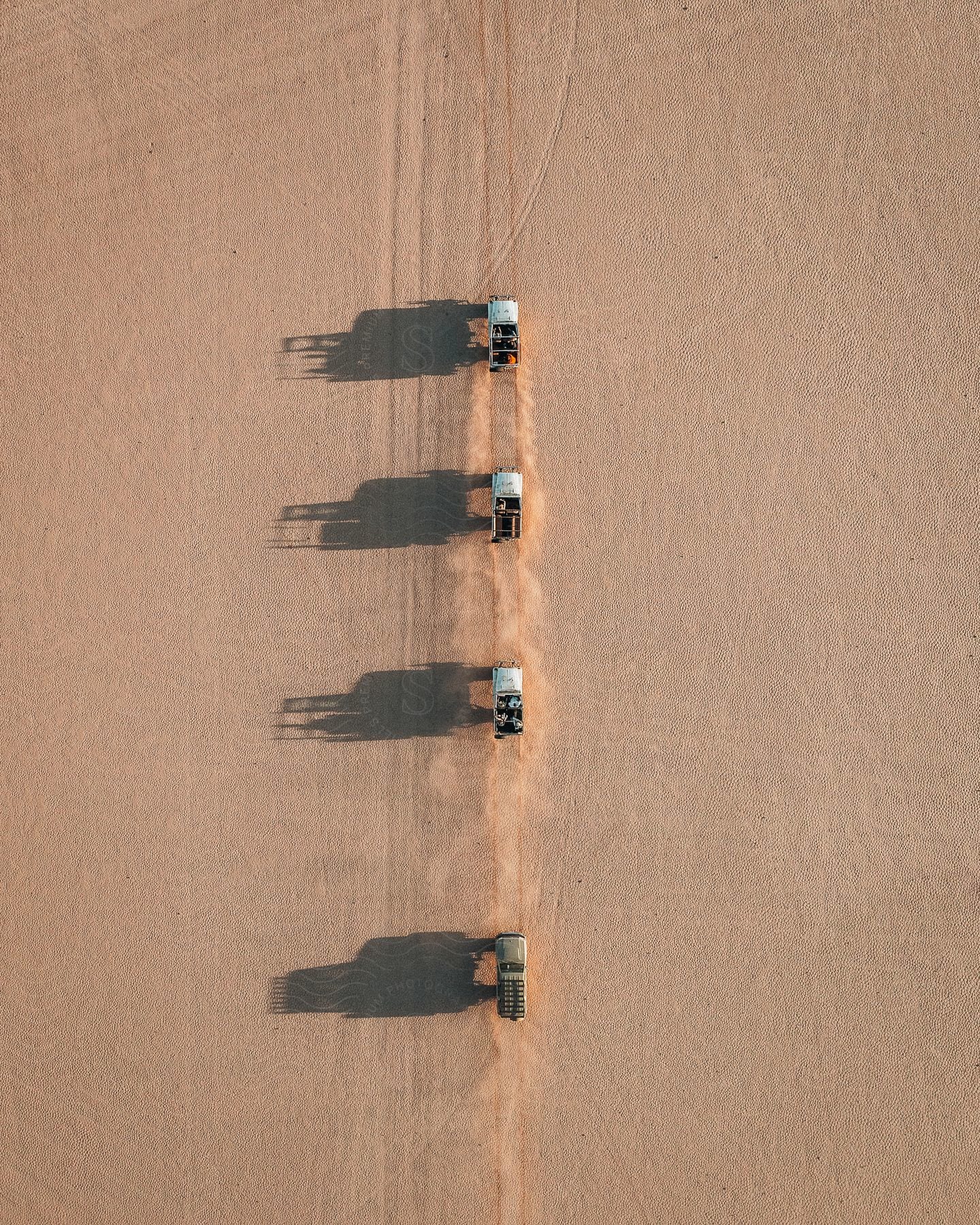 Four cars drive across a dry desert landscape with purpose and adventure