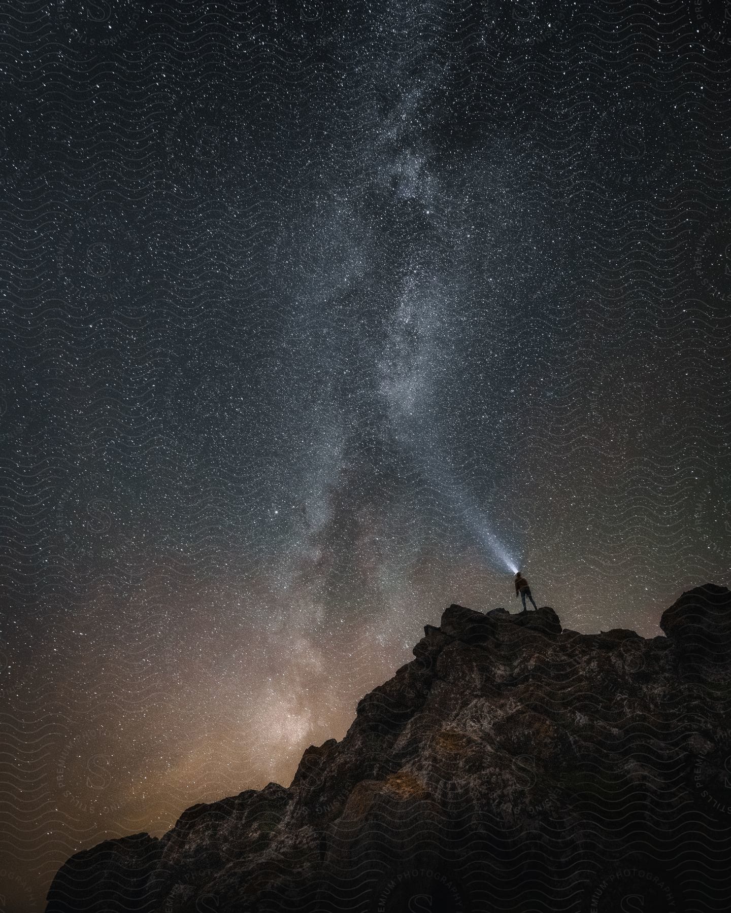 Silhouette of a person standing on a mountain under the milky way stars