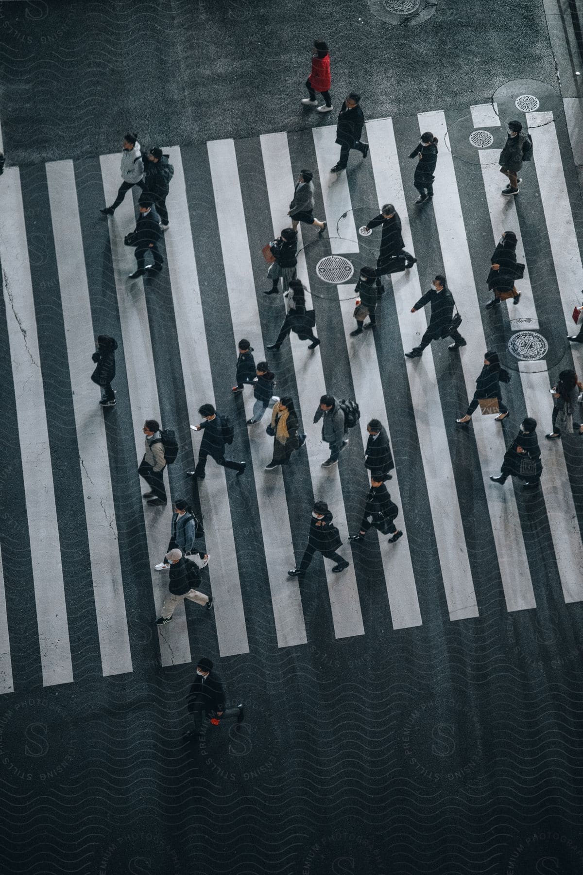 A crowded road with people wearing various clothing and carrying bags and handbags