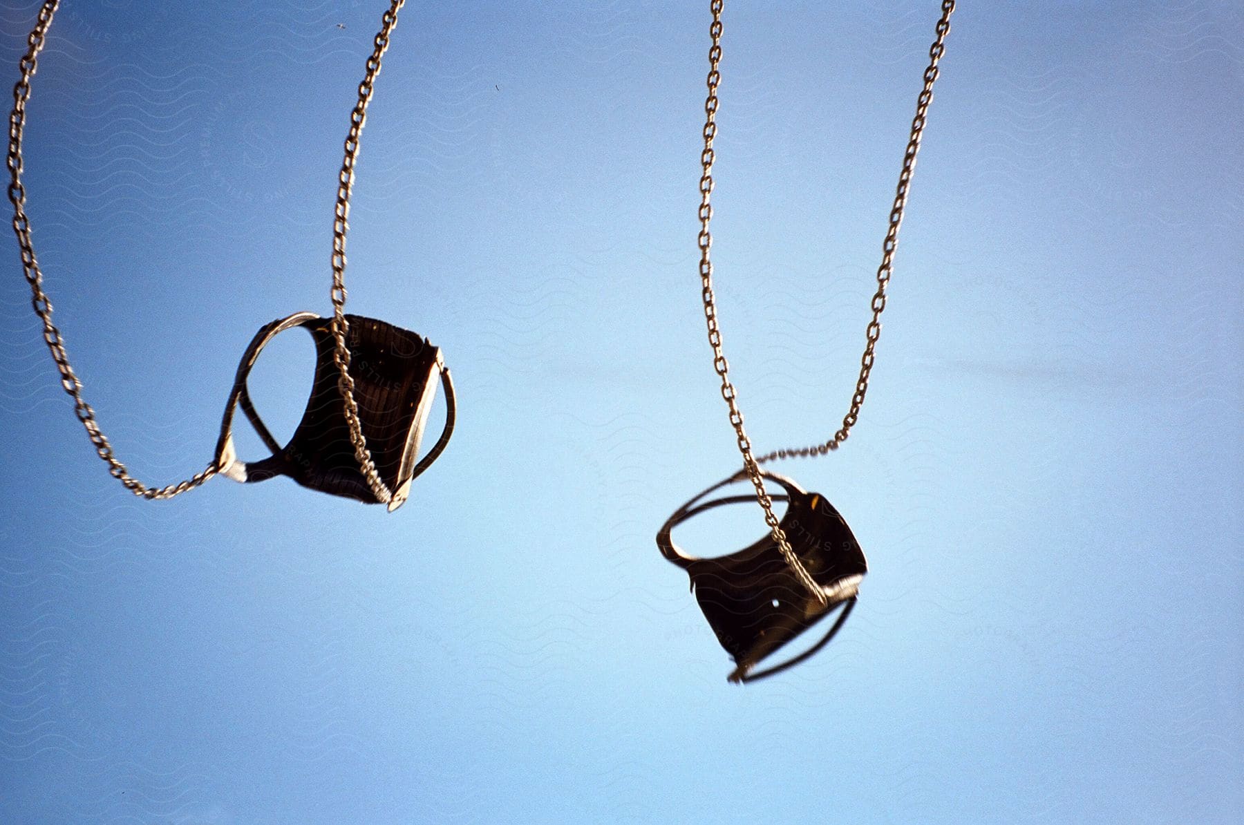 Swings with chains thrown up in the air under a blue sky during the day