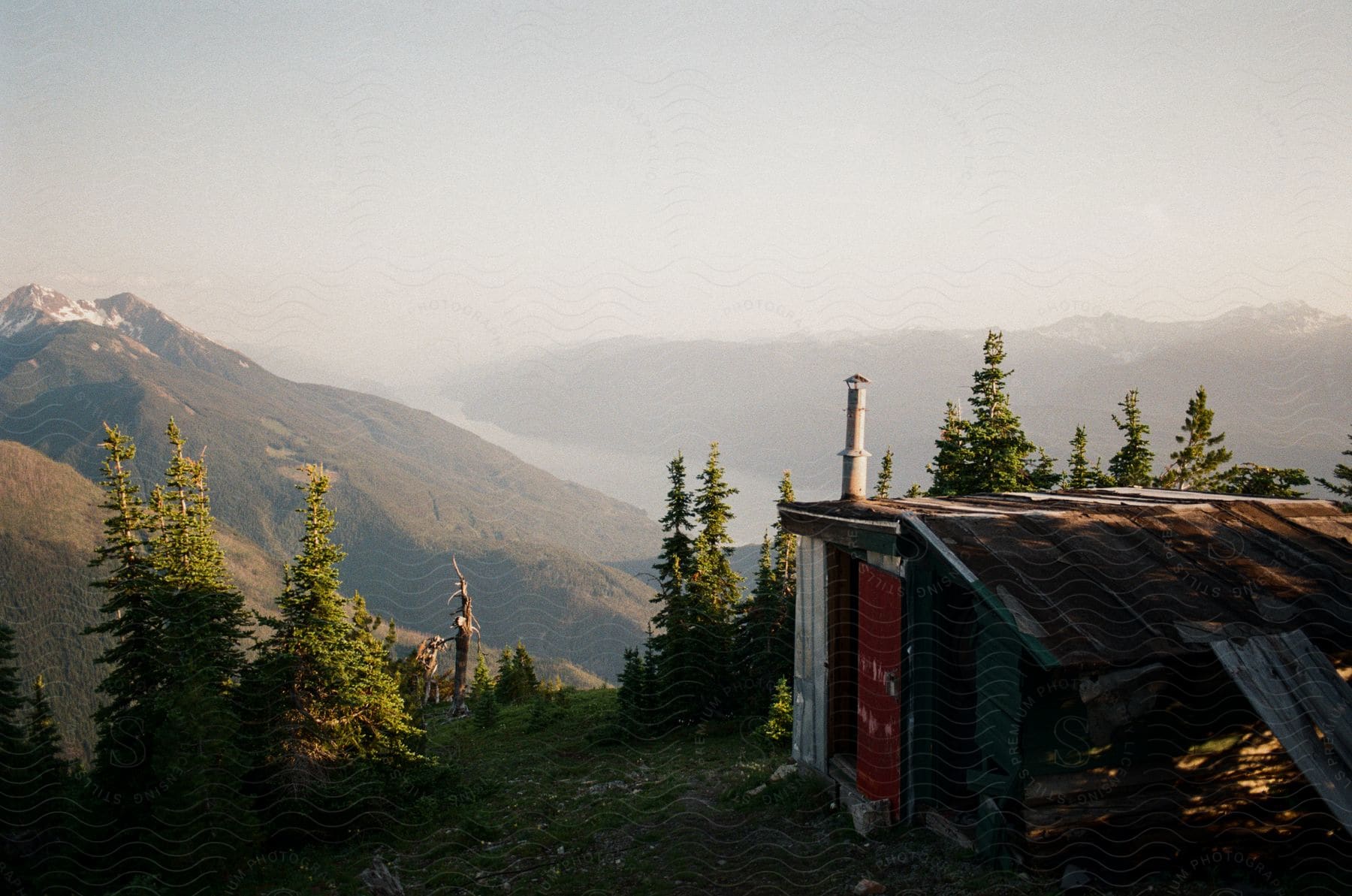 An old cabin sits atop a mountain offering a picturesque valley landscape