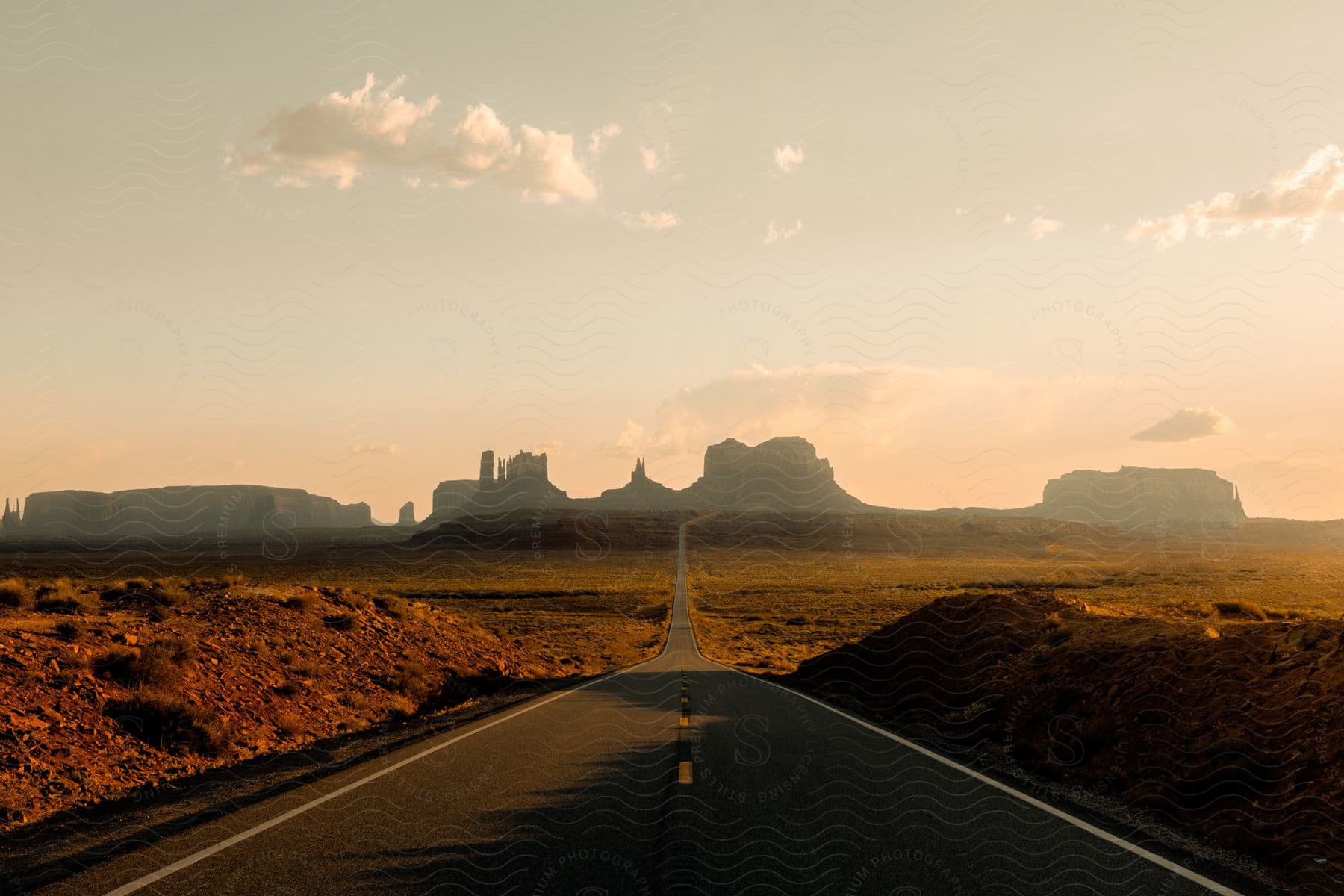 A winding road surrounded by rocky terrain and a cloudy sky in the evening