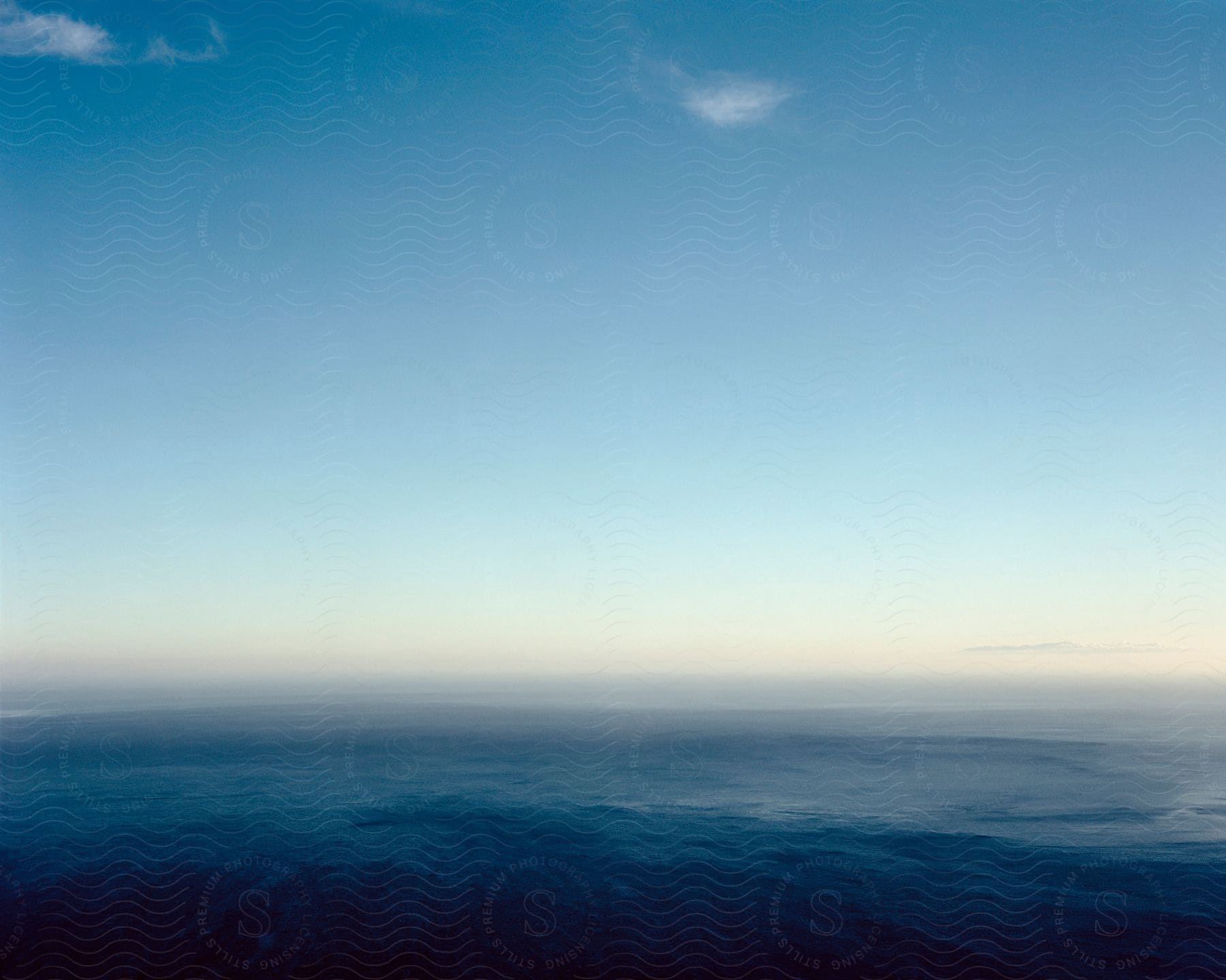 Aerial shot of open sea with blue sky and white clouds