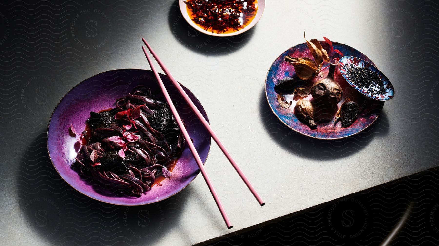 Asian food on three different plates presented on a table with chopsticks