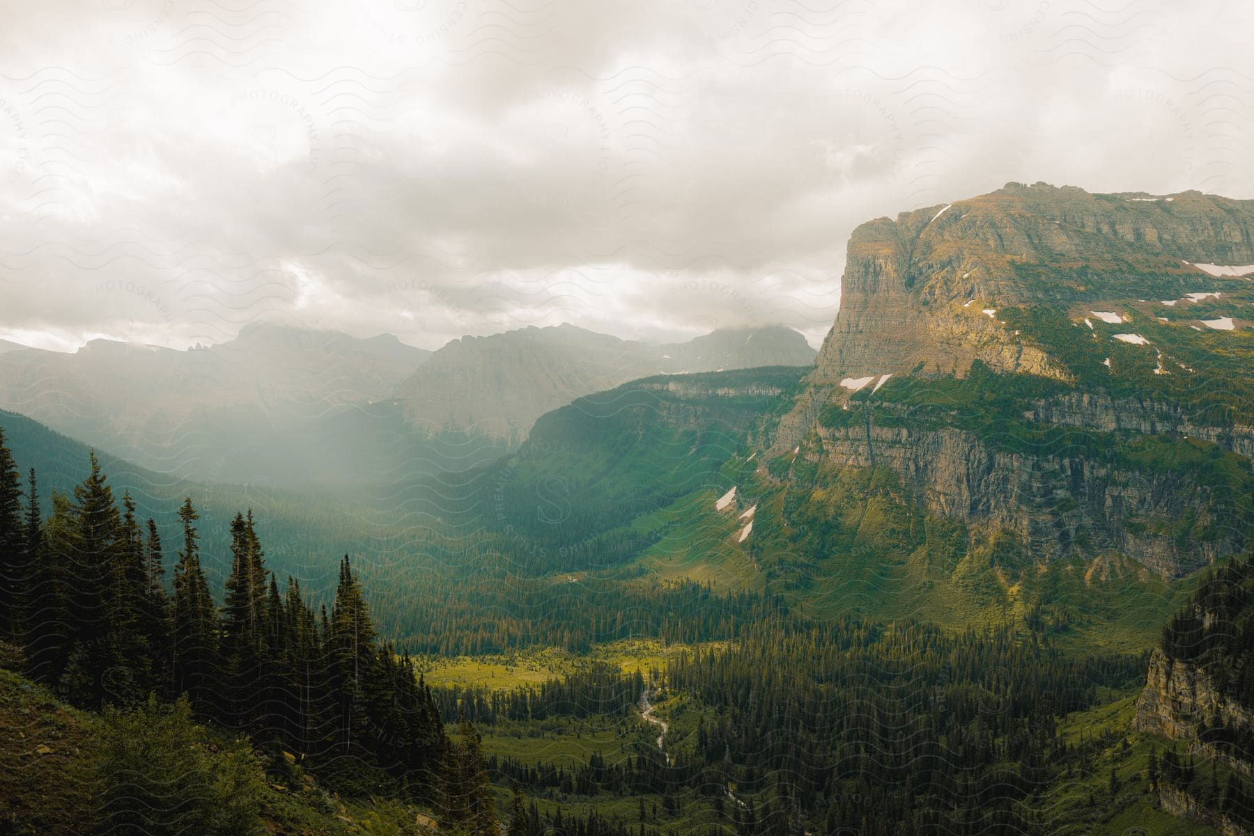 Sunlight shines through clouds over a mountain valley