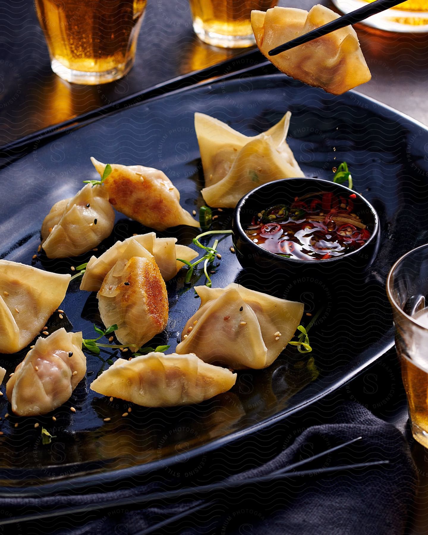 Dumplings on a black plate with a small bowl of dipping sauce