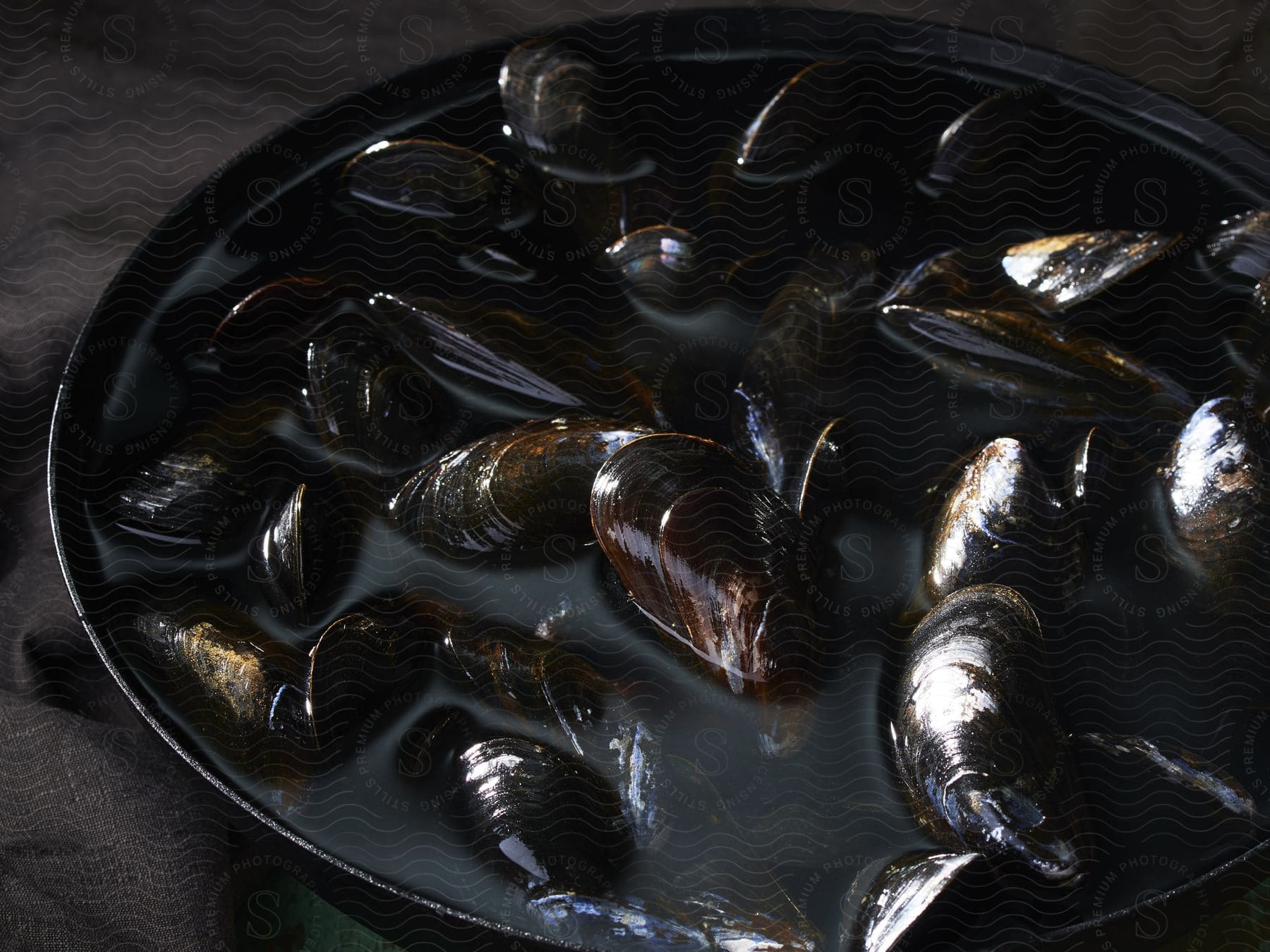 Pot of mussels filled with water on a grey tablecloth
