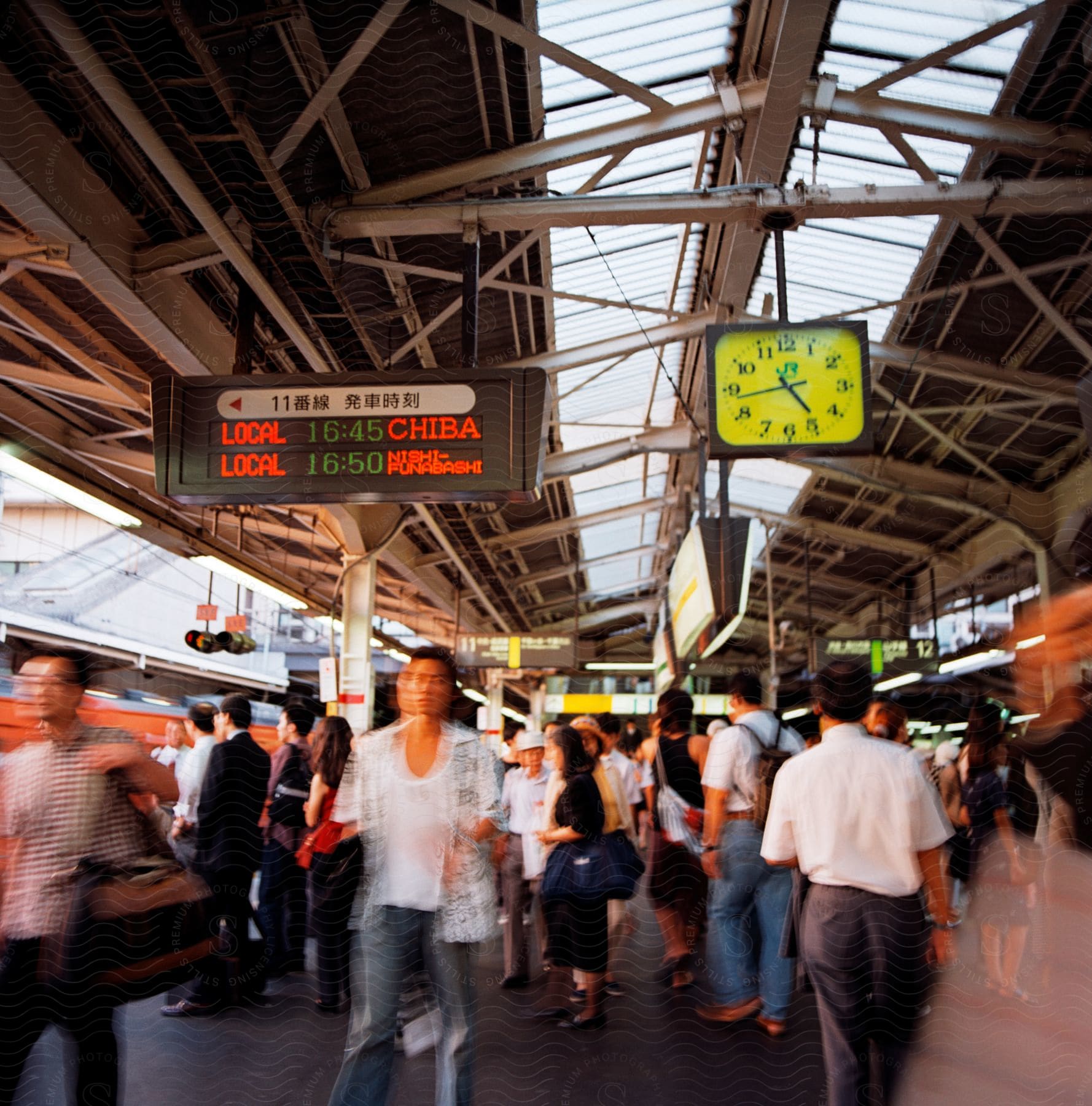 A busy train station with a crowd of people moving around some carrying bags