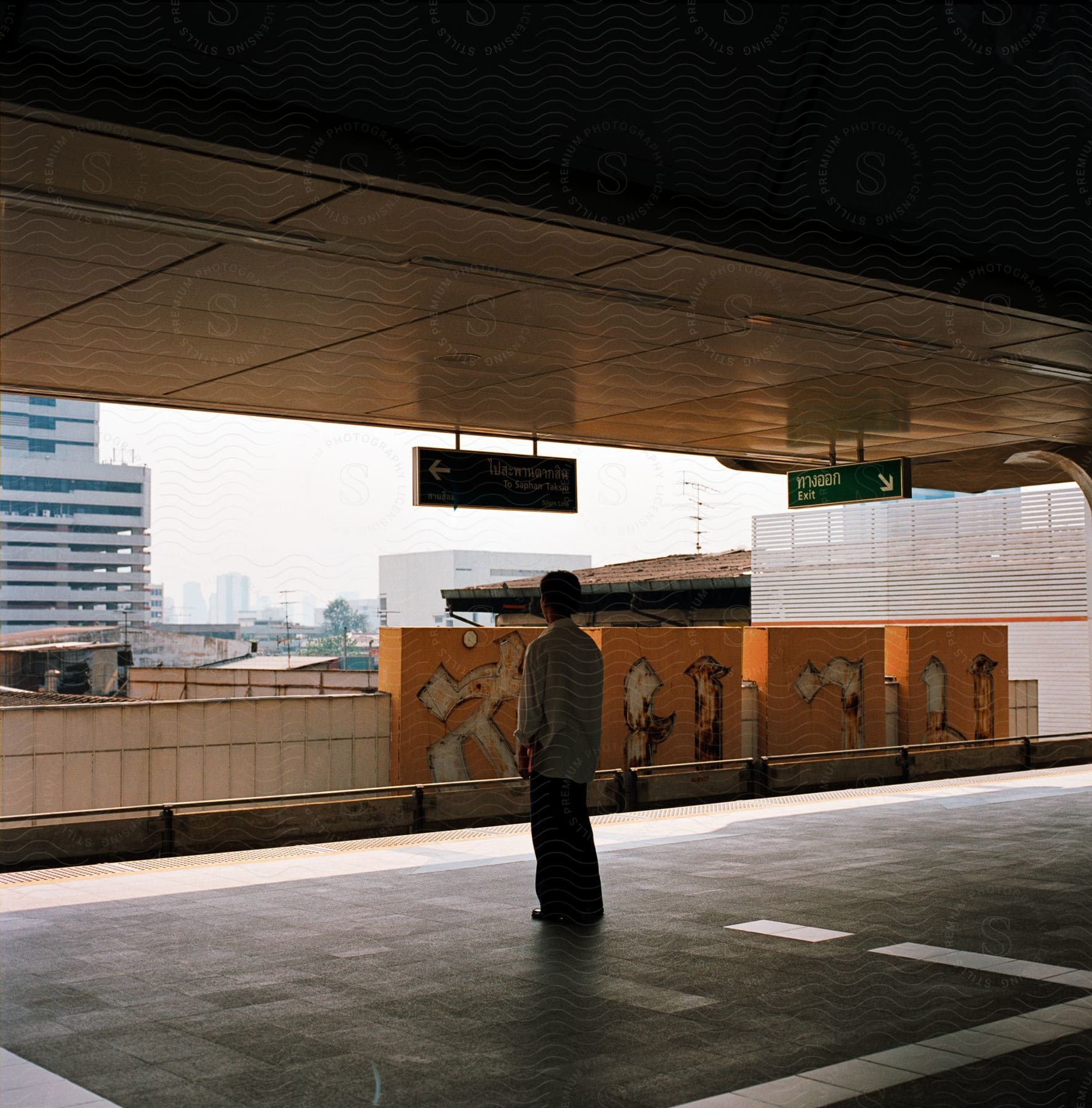 A man standing in an empty parking lot with buildings in the background