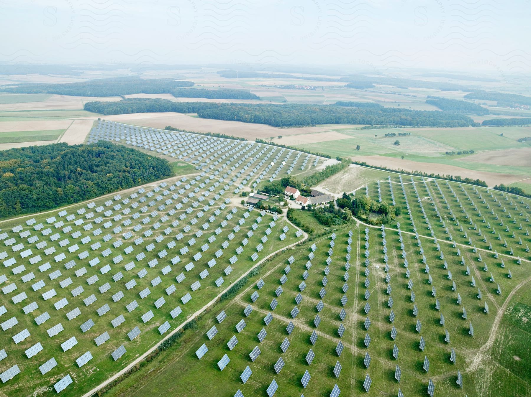 Stock photo of panels in solar farm stretch across fields on foggy day