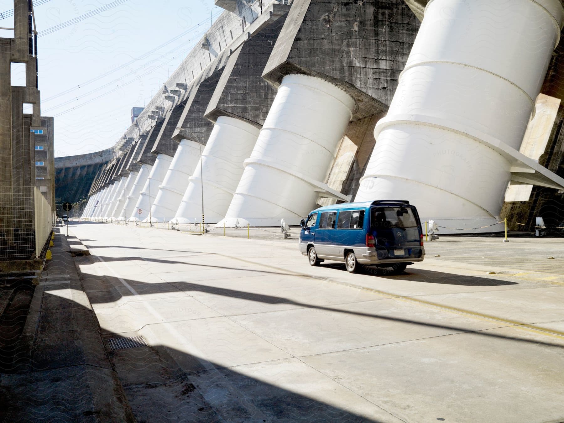 Blue van driving on a highway surrounded by giant concrete columns