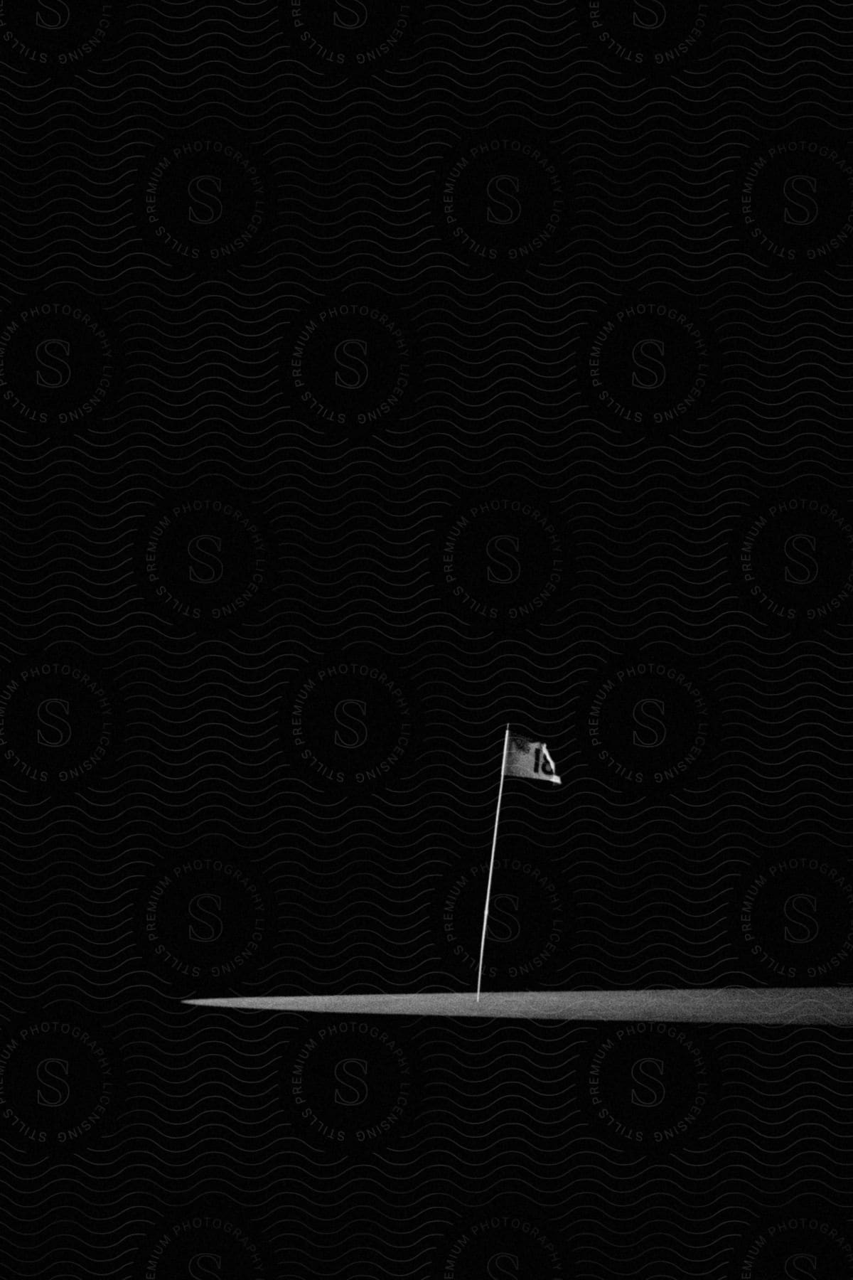 A black and white image of a flag in a very dark outdoor environment at night time