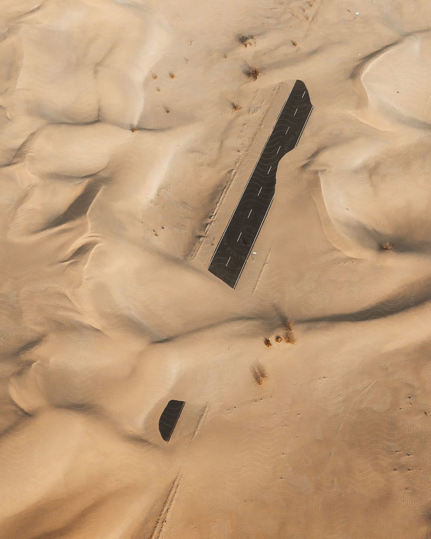 Stock photo of highway covered with sand in the desert as seen from above