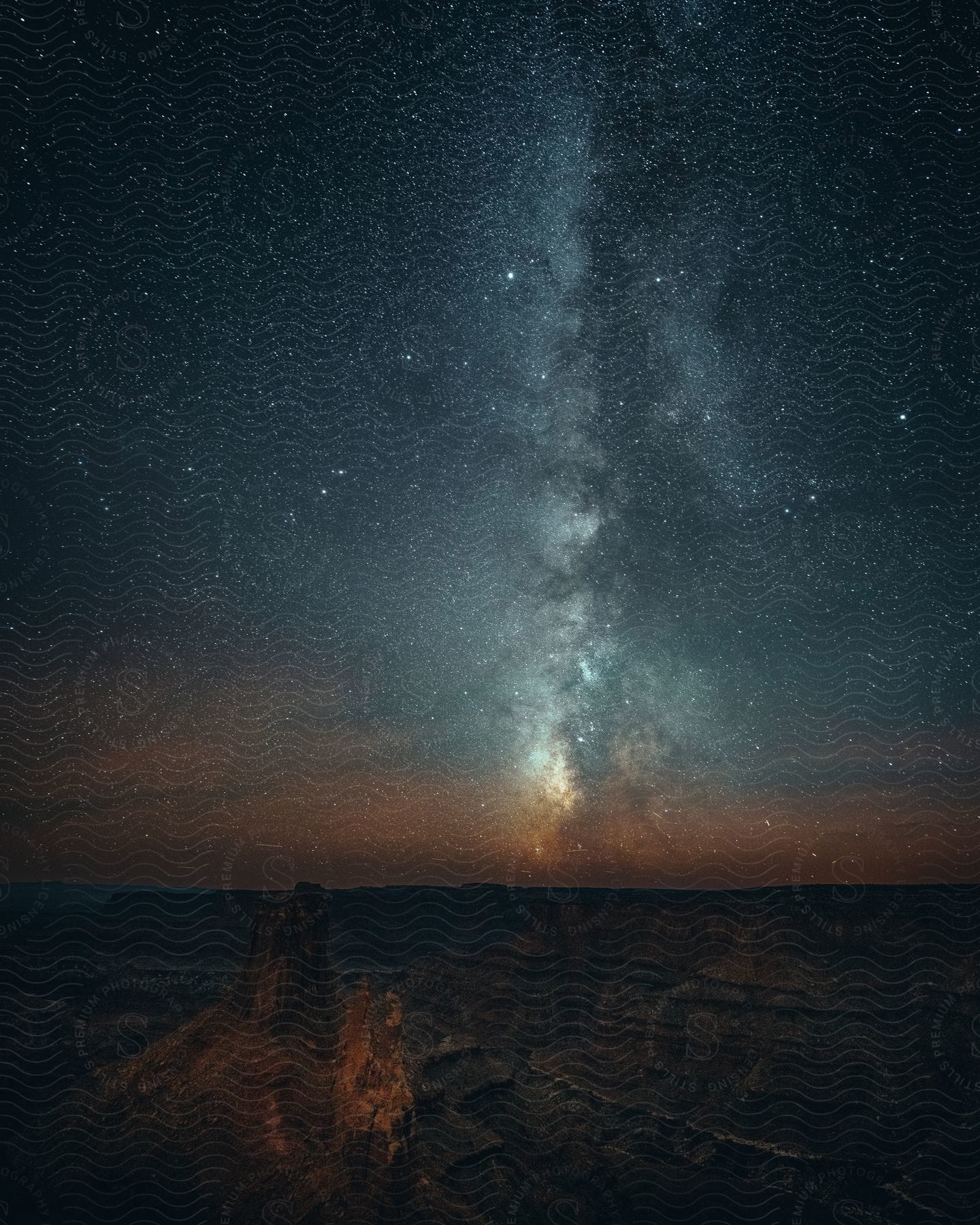 A bright constellation shines over a rocky canyon at night