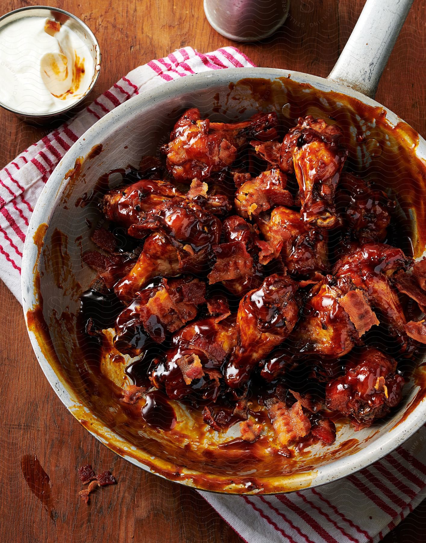 Stock photo of honey bbq chicken thigh resting on a napkin on a table alongside whipped cream