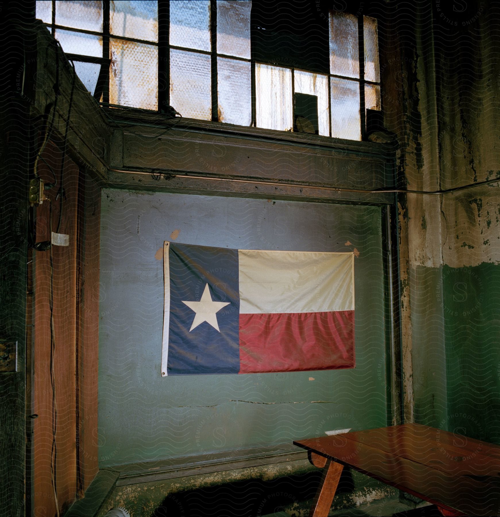 A Flag Hangs Inside An Old Building With Chipping Paint And Dirty Windows