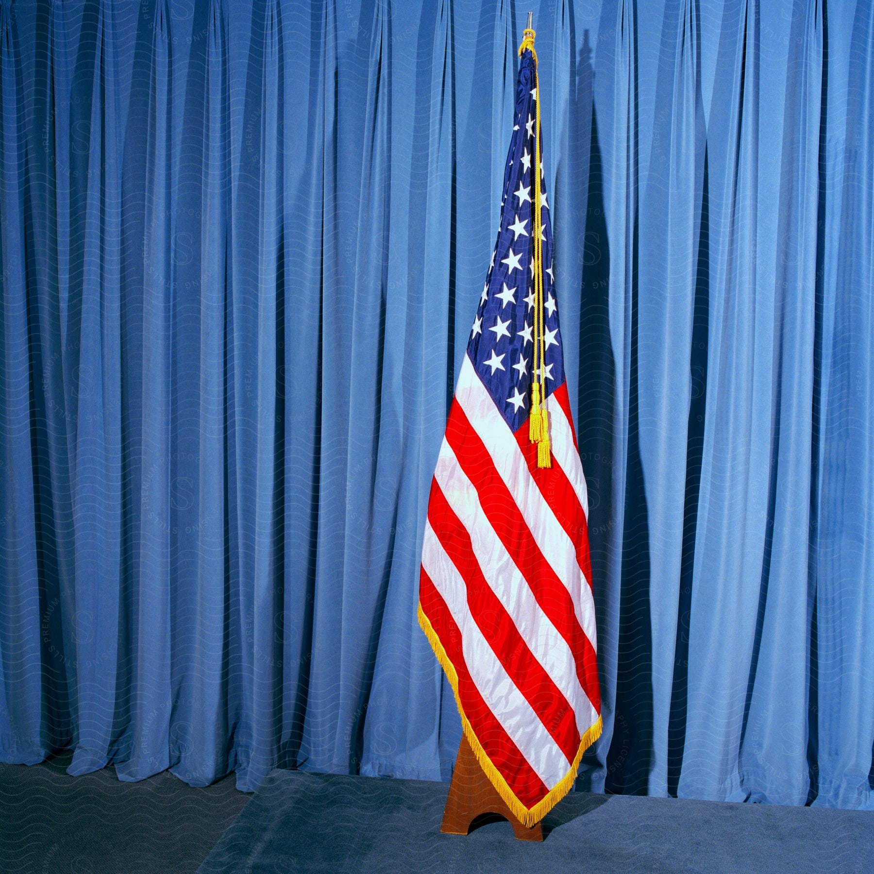 An american flag draped in front of a blue curtain on top of blue carpet