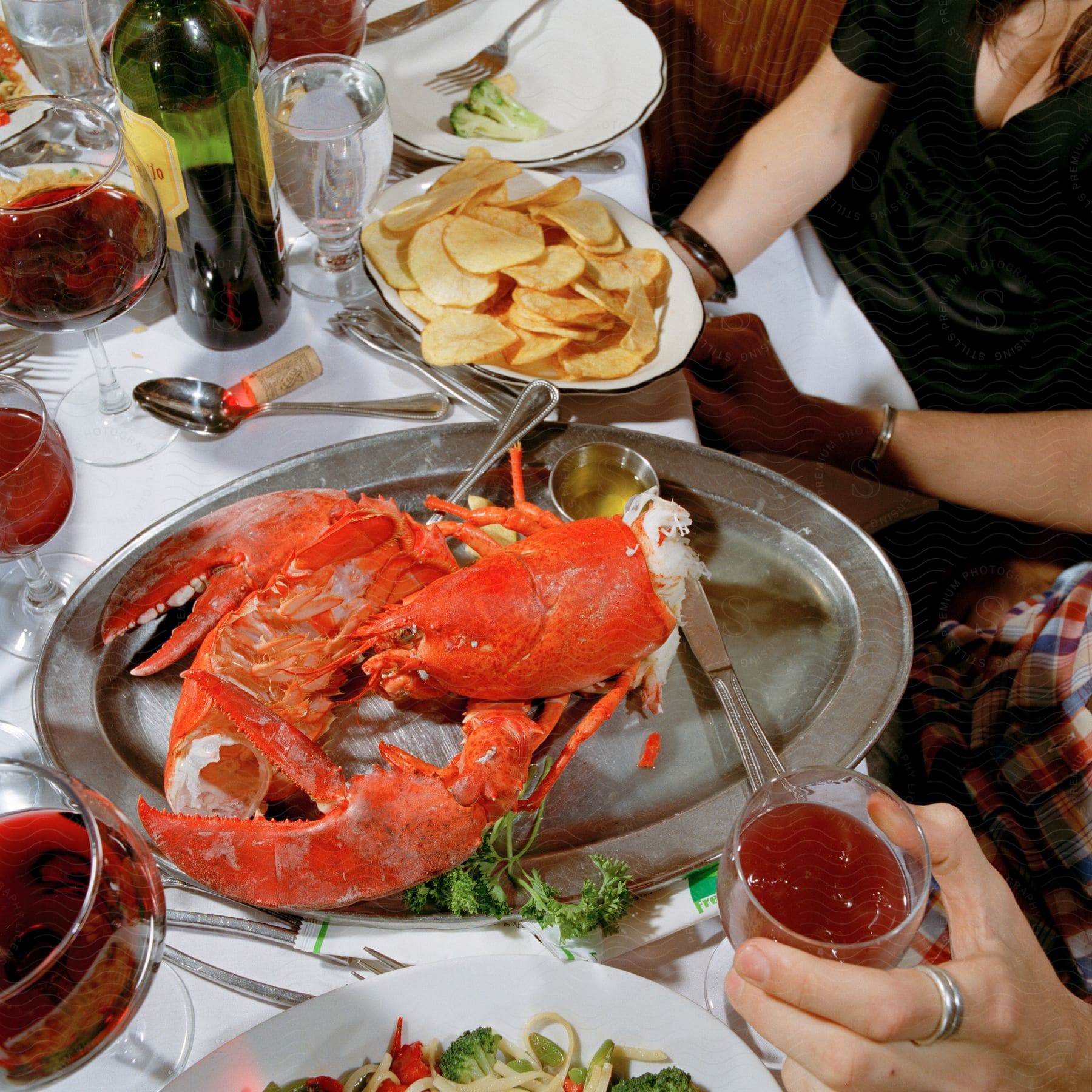 A man and a woman sit at a table with a lobster platter and wine