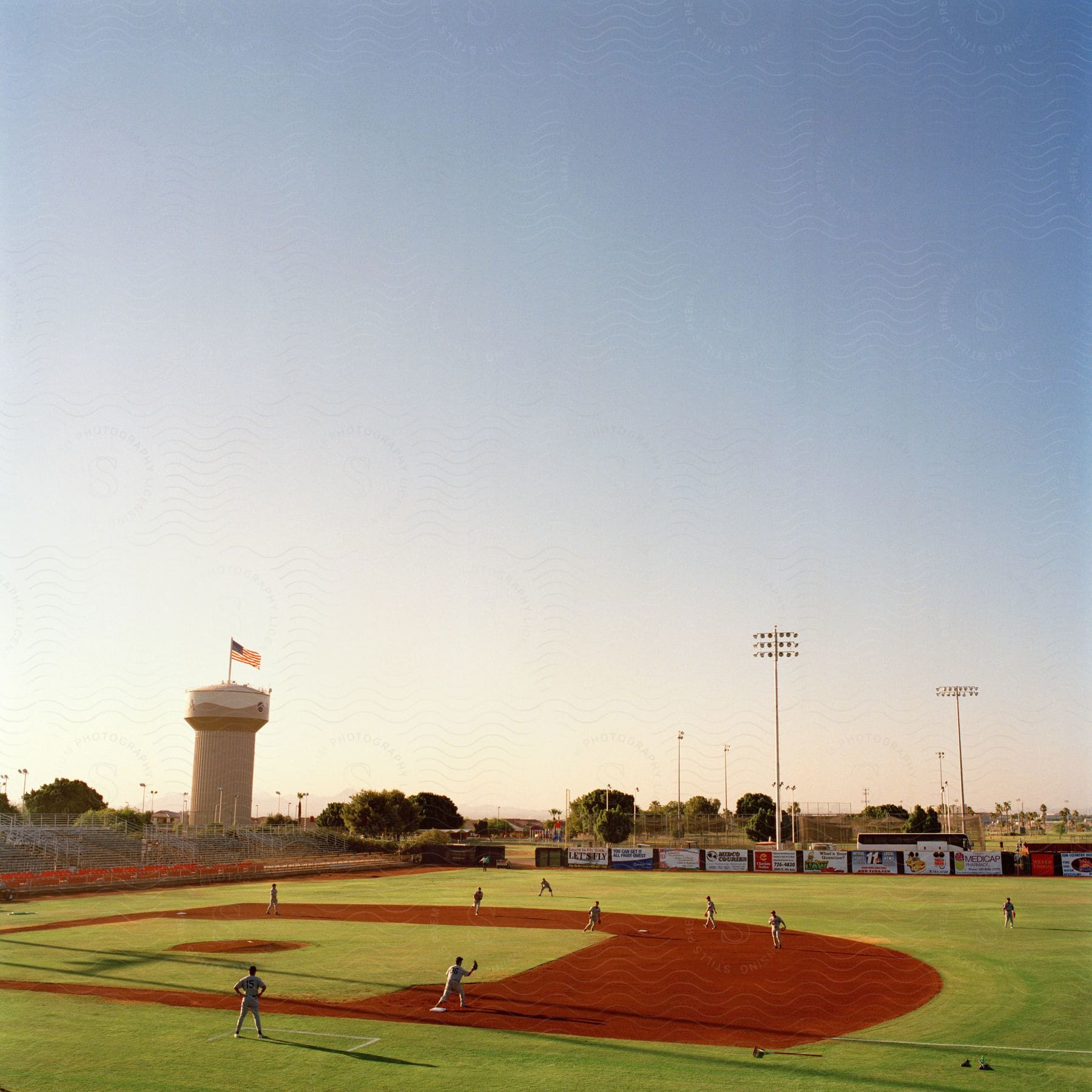 A baseball team practices playing on a baseball field on a sunny day with a cloudless blue sky