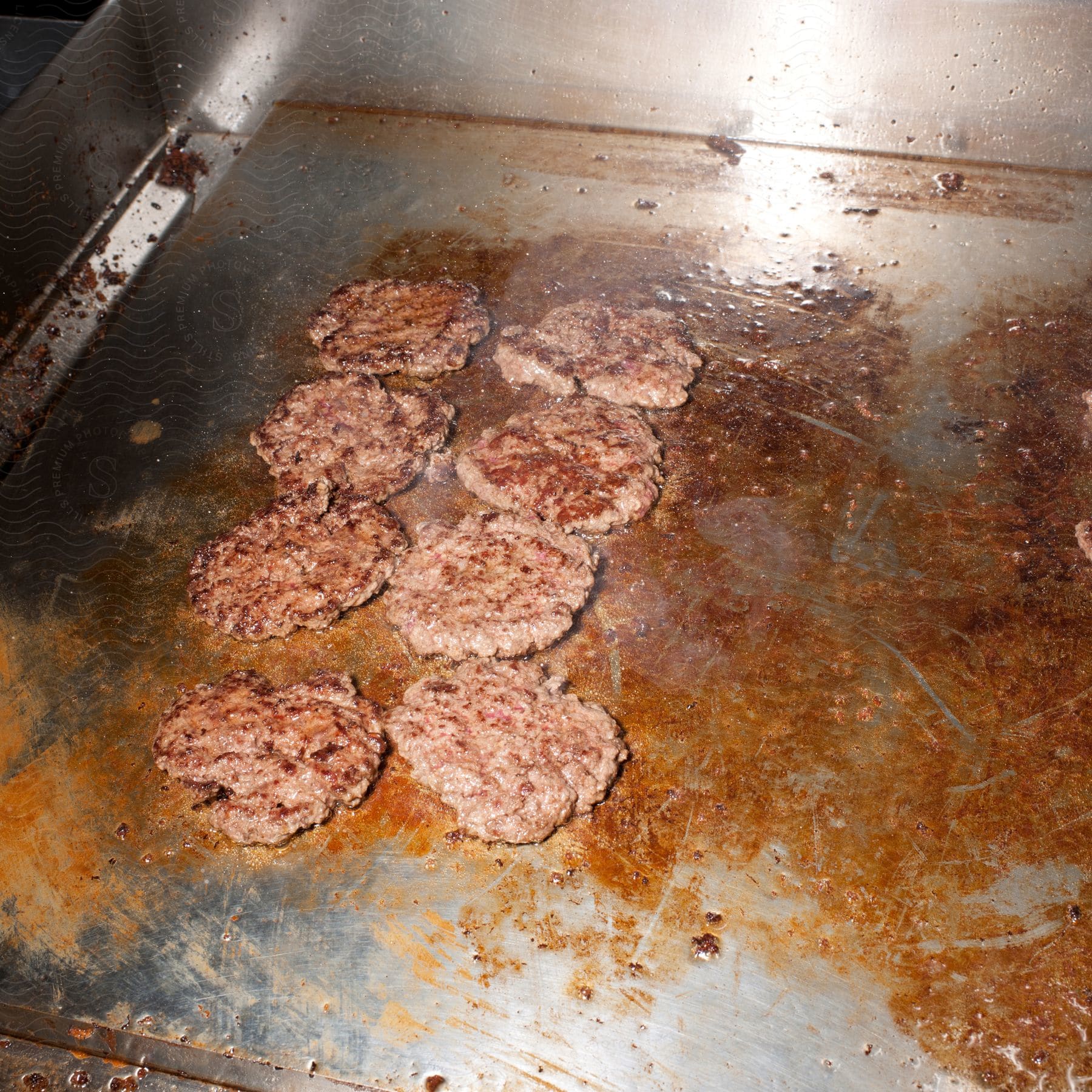 A hamburger is being cooked on an iron griddle