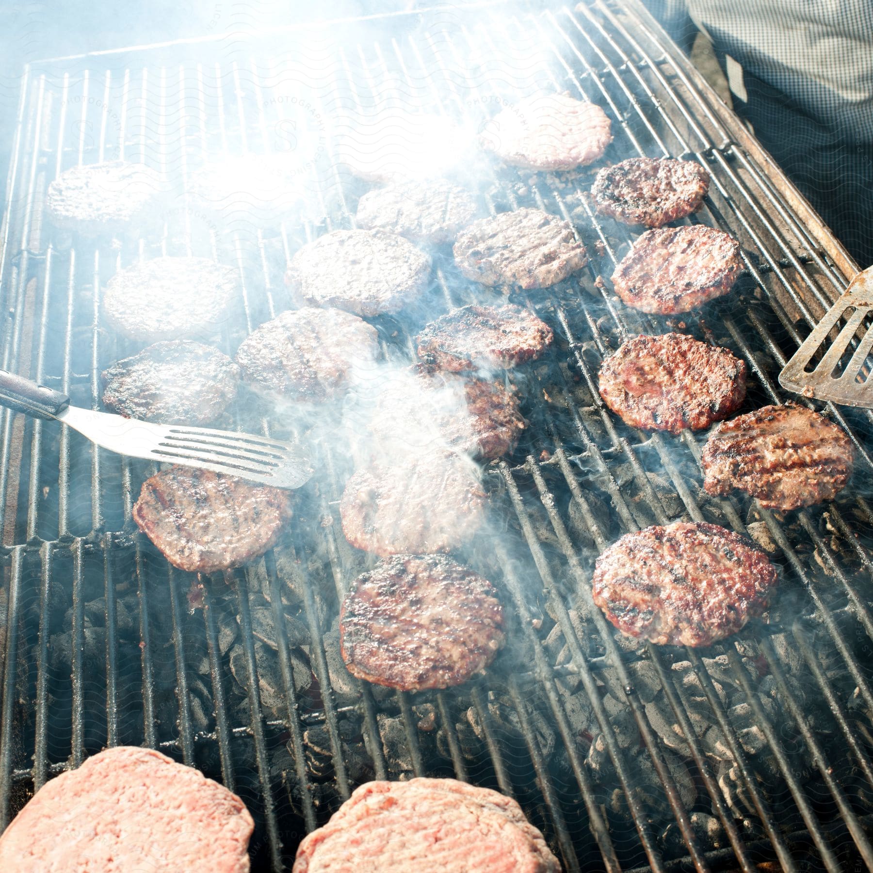 A man is cooking burgers on a griddle