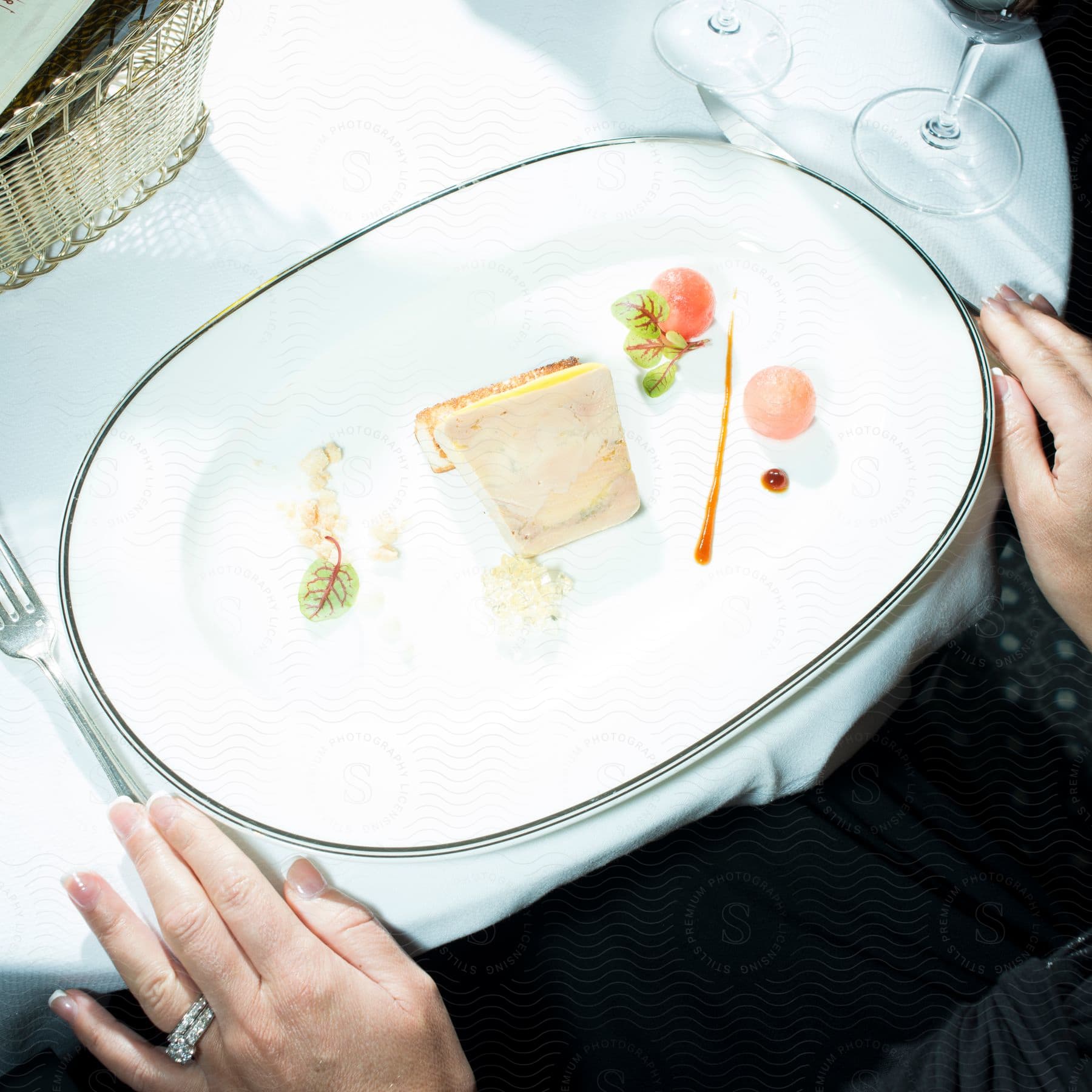 A woman sitting at a restaurant table with a plate of food and a wine glass