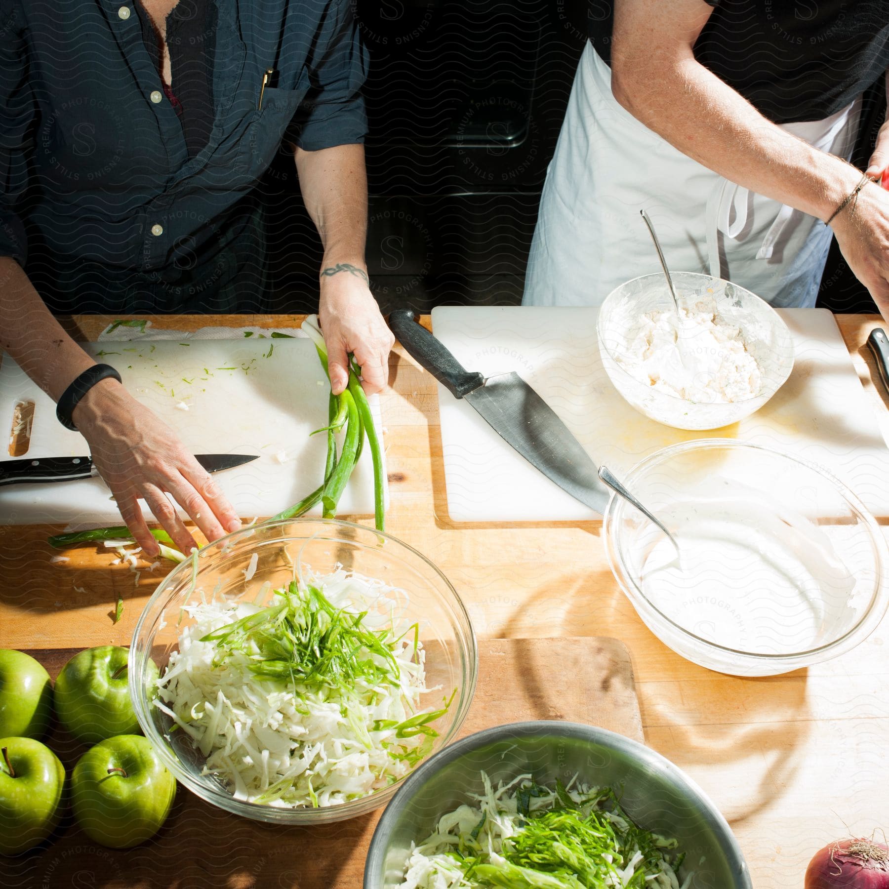 Two chefs preparing food at a counter with bowls of vegetables and fruits