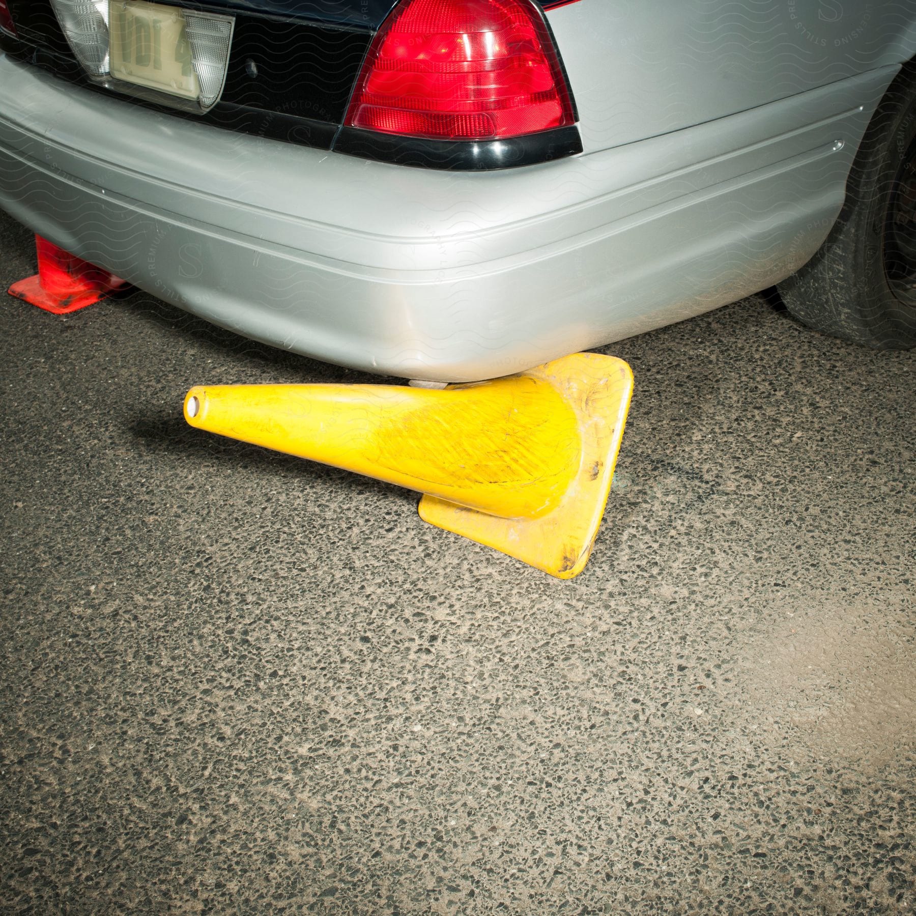 A car knocks over a yellow safety cone while backing up