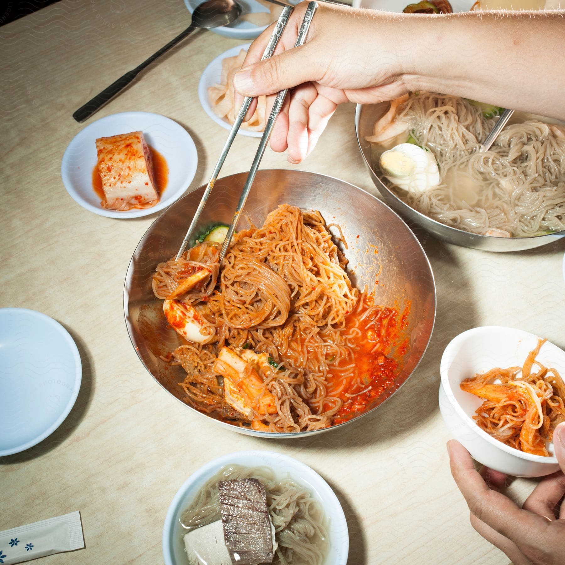 A person places asian cuisine into a white bowl