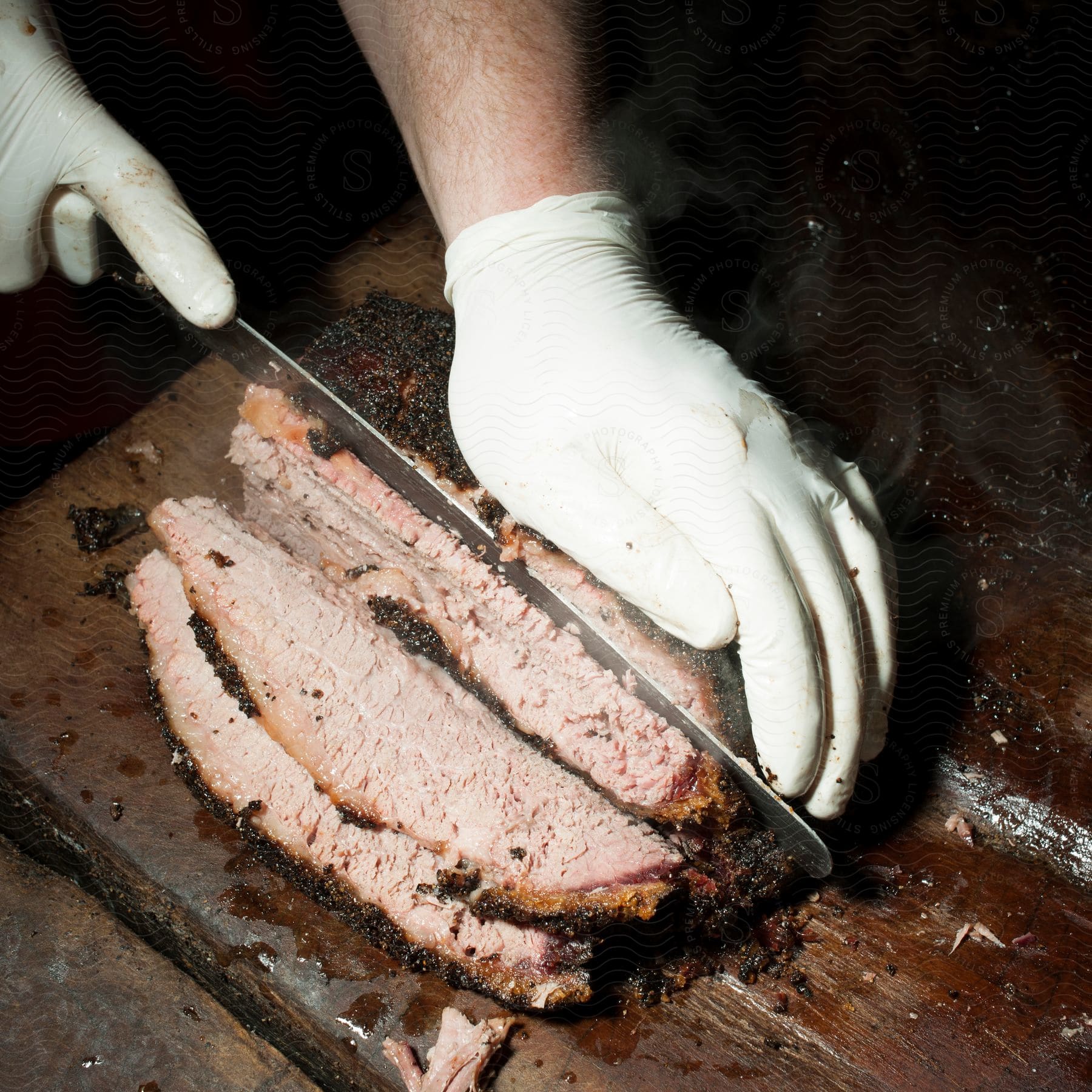 A hand uses a knife to slice brisket on a cutting board