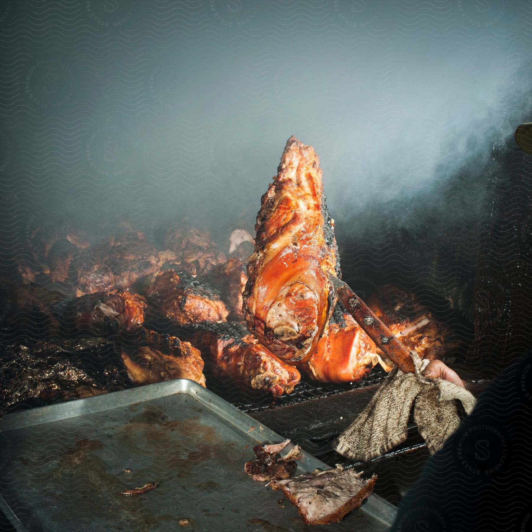 A person is cooking meat on a large barbecue grill