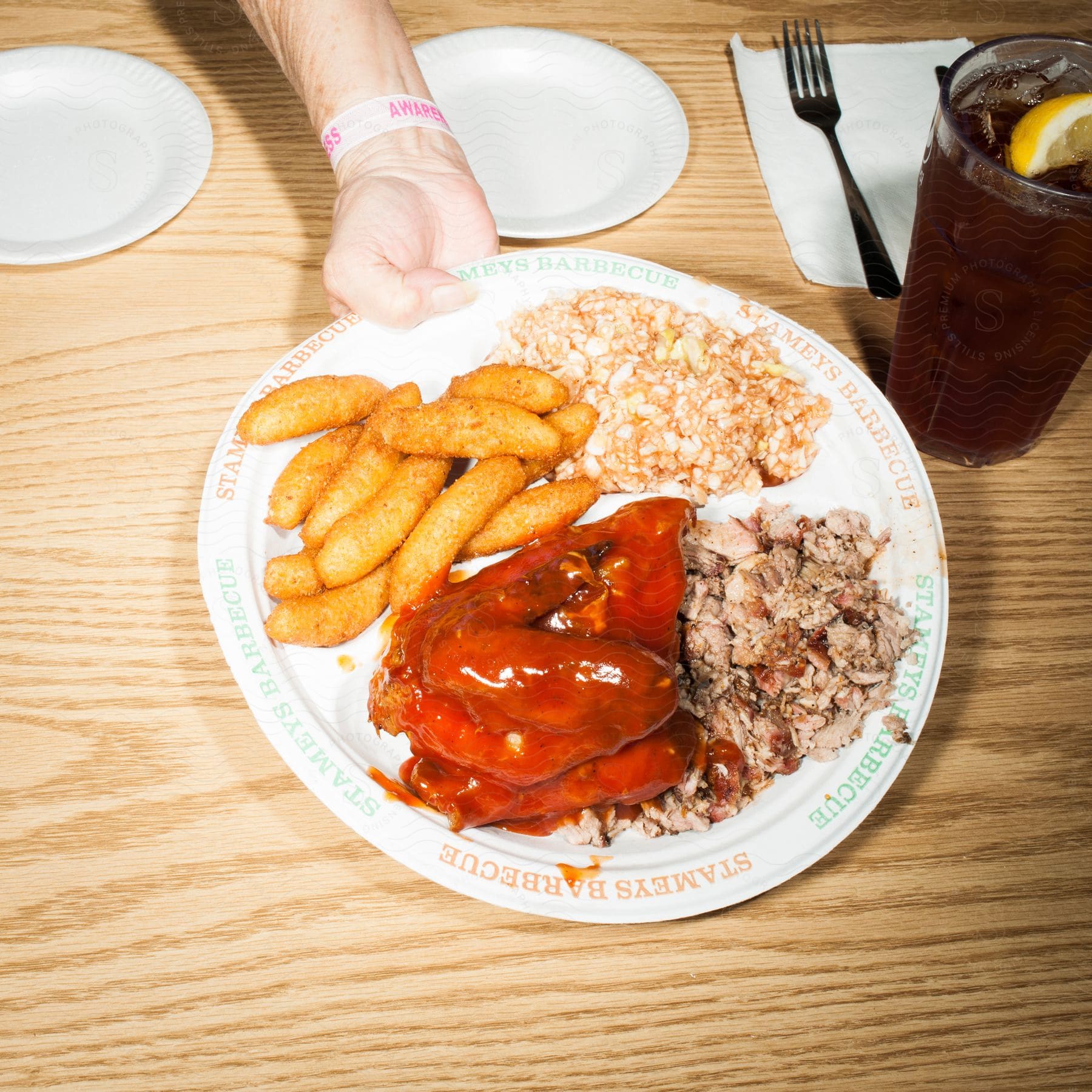 A hand serving a plate with a full hearty meal on a table
